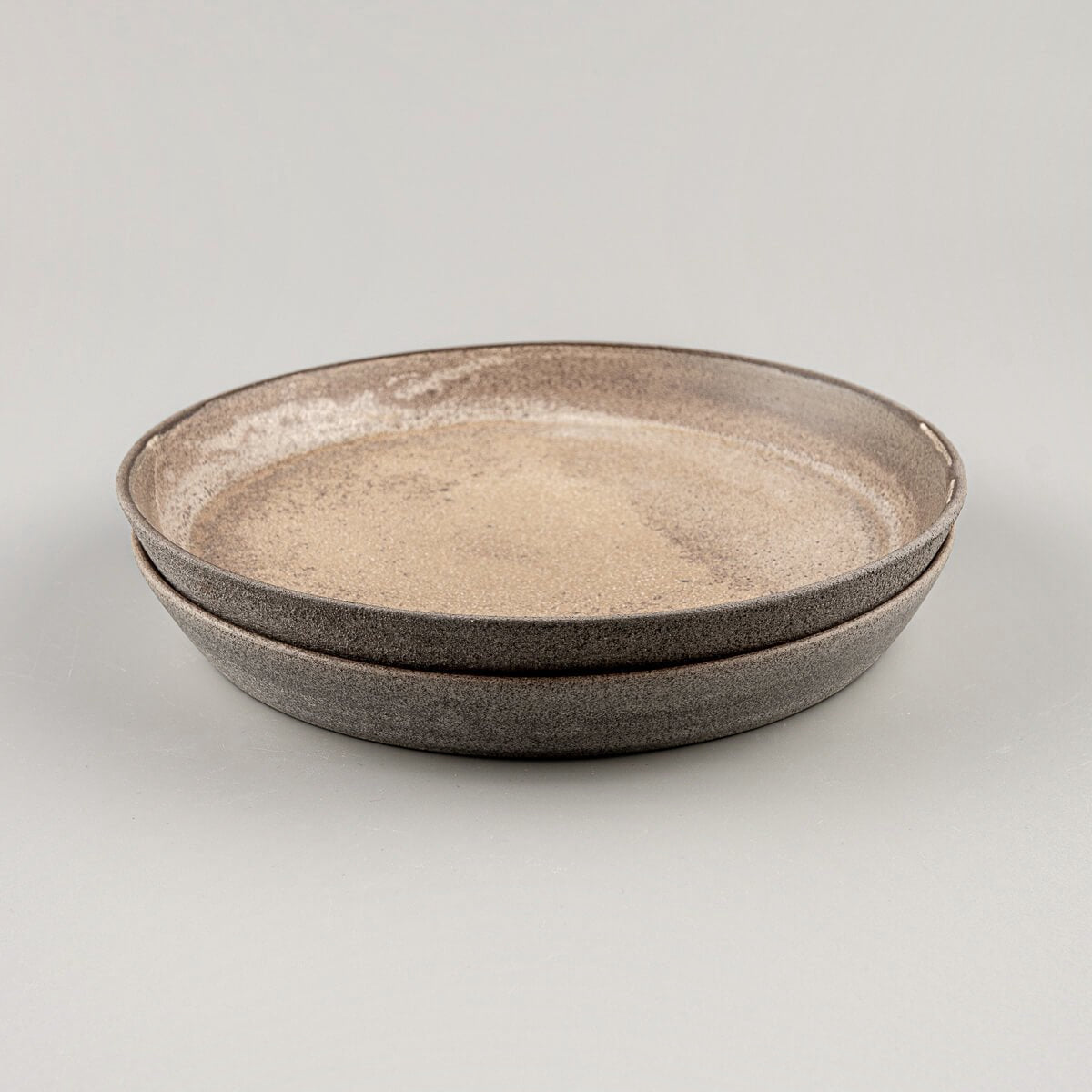 Stacked stoneware dinner plates with refined coupe design.