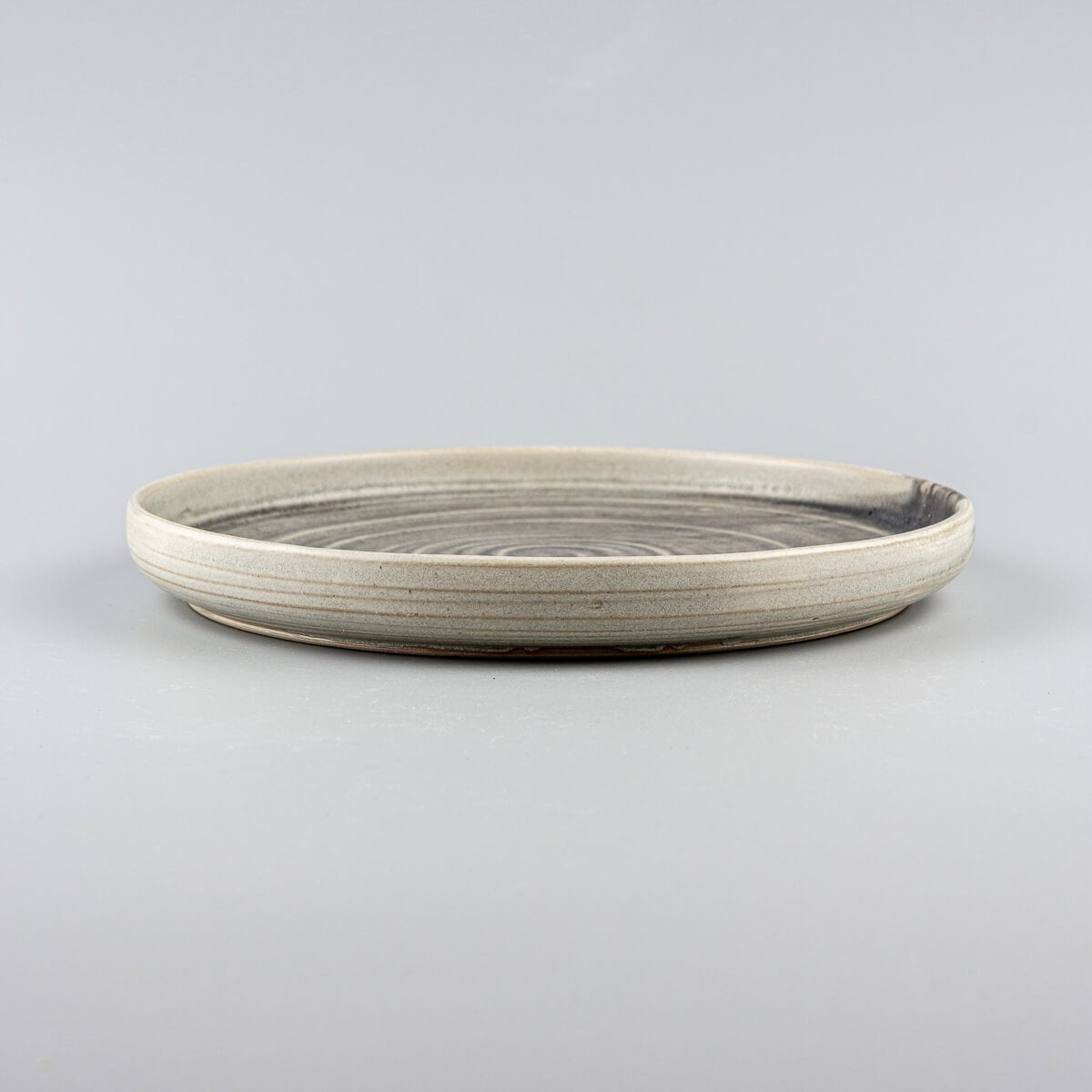 Side view of artisanal ceramic plates with gently curved edges and premium craftsmanship.
