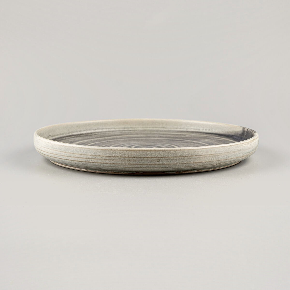 Side view of artisanal ceramic plates with gently curved edges and premium craftsmanship.