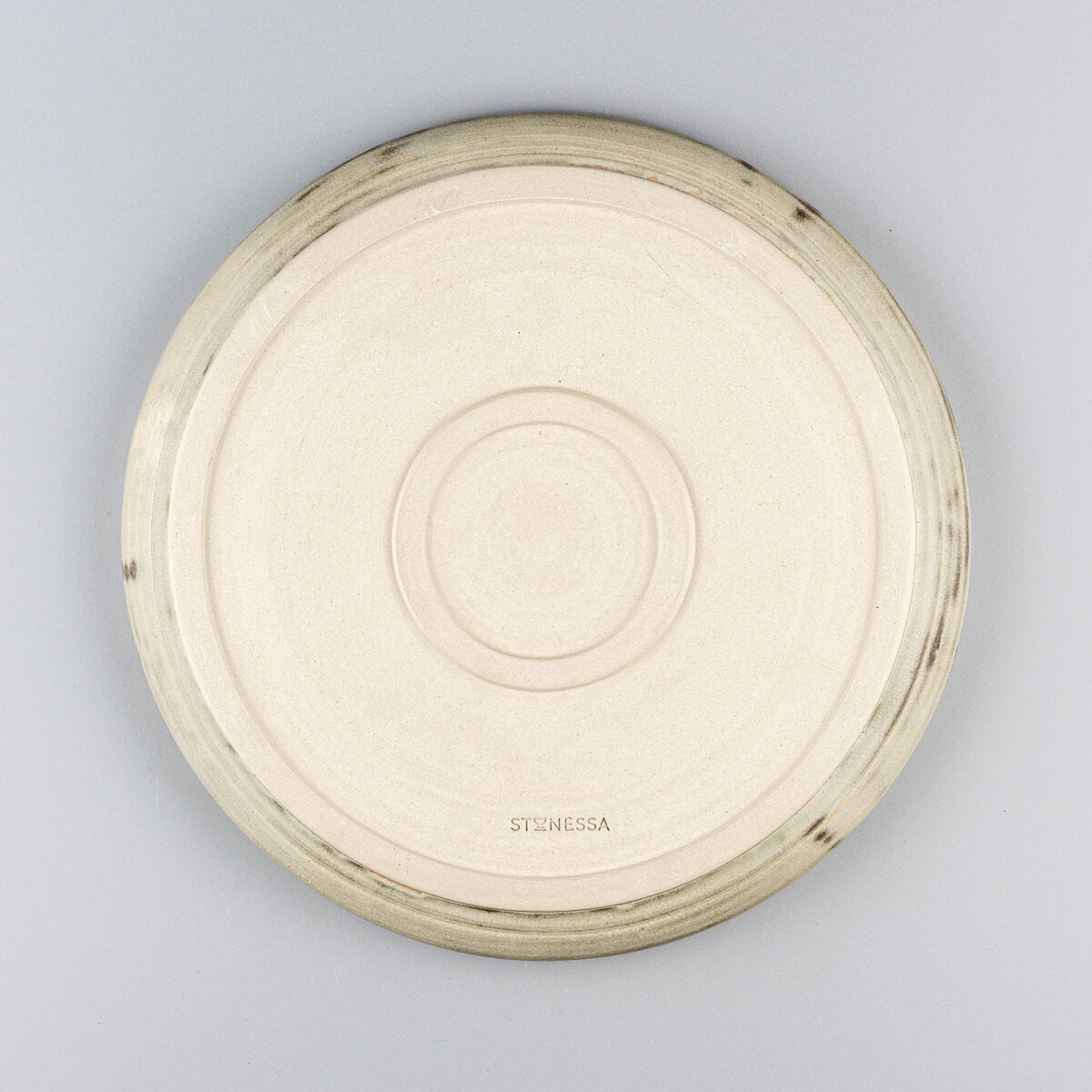 Unglazed underside of handcrafted ceramic plate with distinctive double foot for stability.