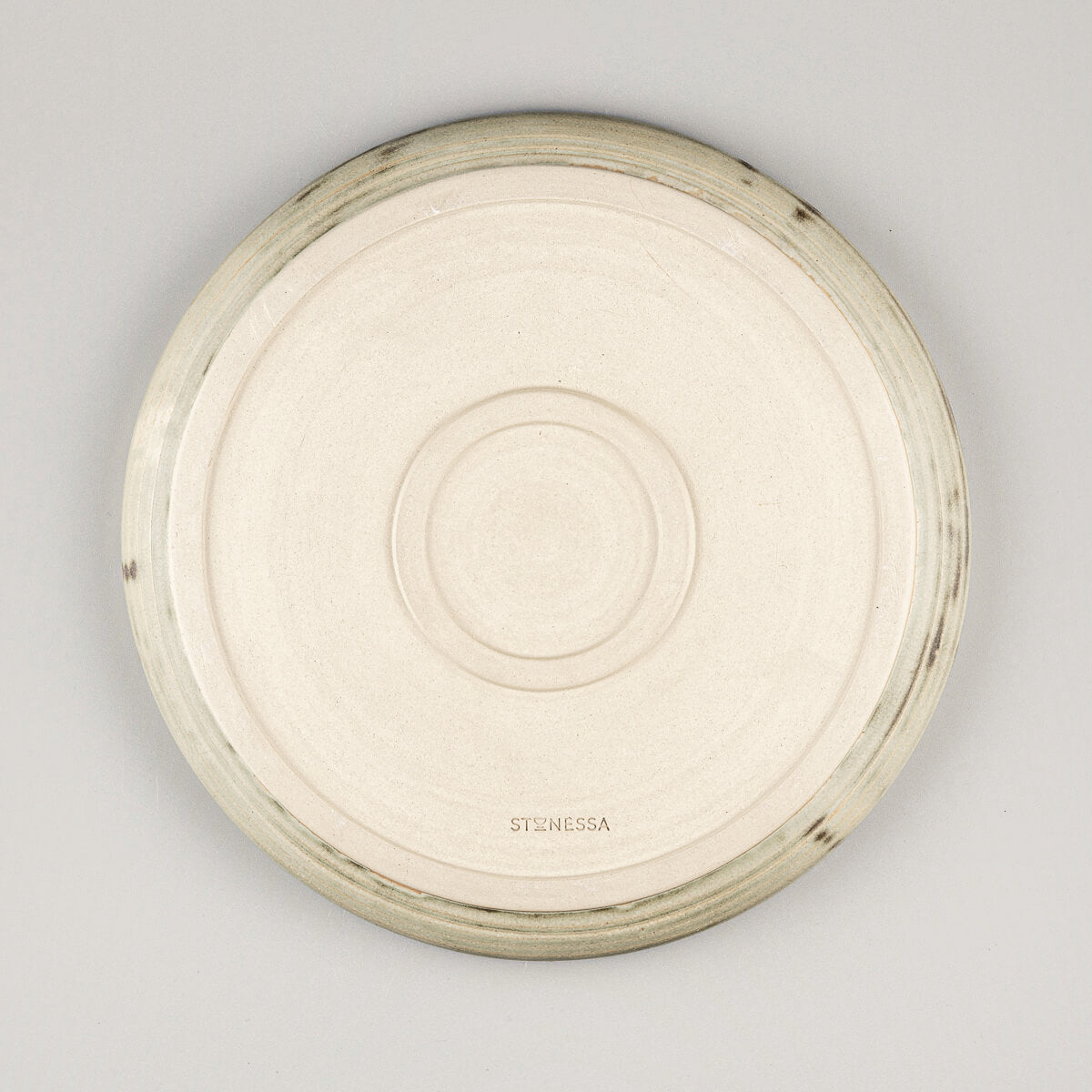 Unglazed underside of handcrafted ceramic plate with distinctive double foot for stability.