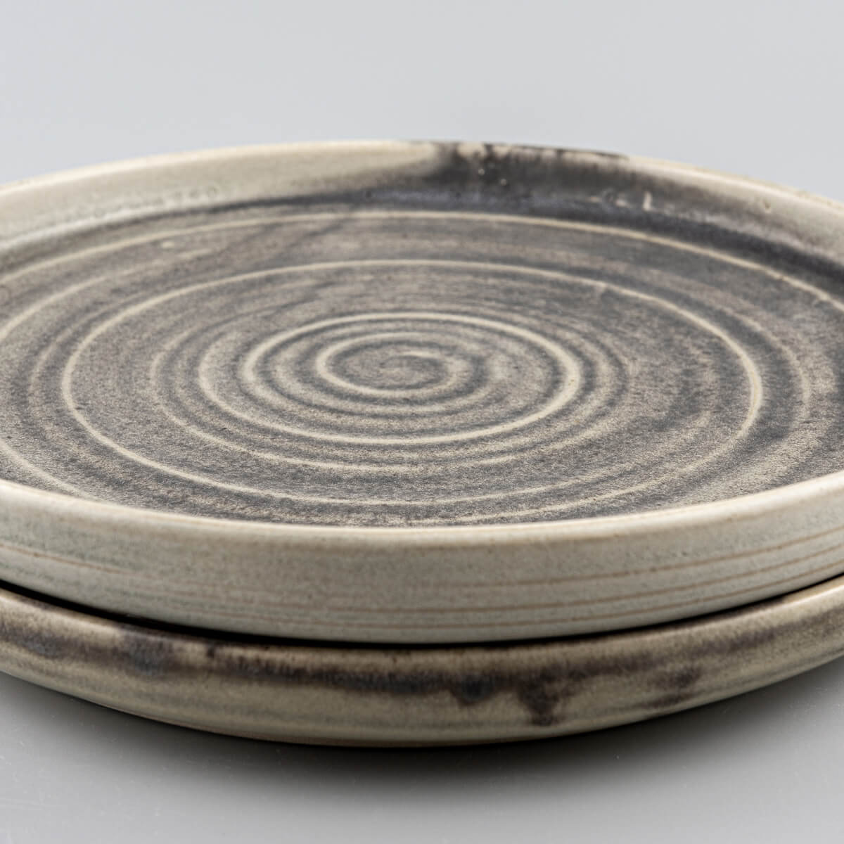 Artisanal ceramic plates close-up with precision-crafted spiral design and textured surface.