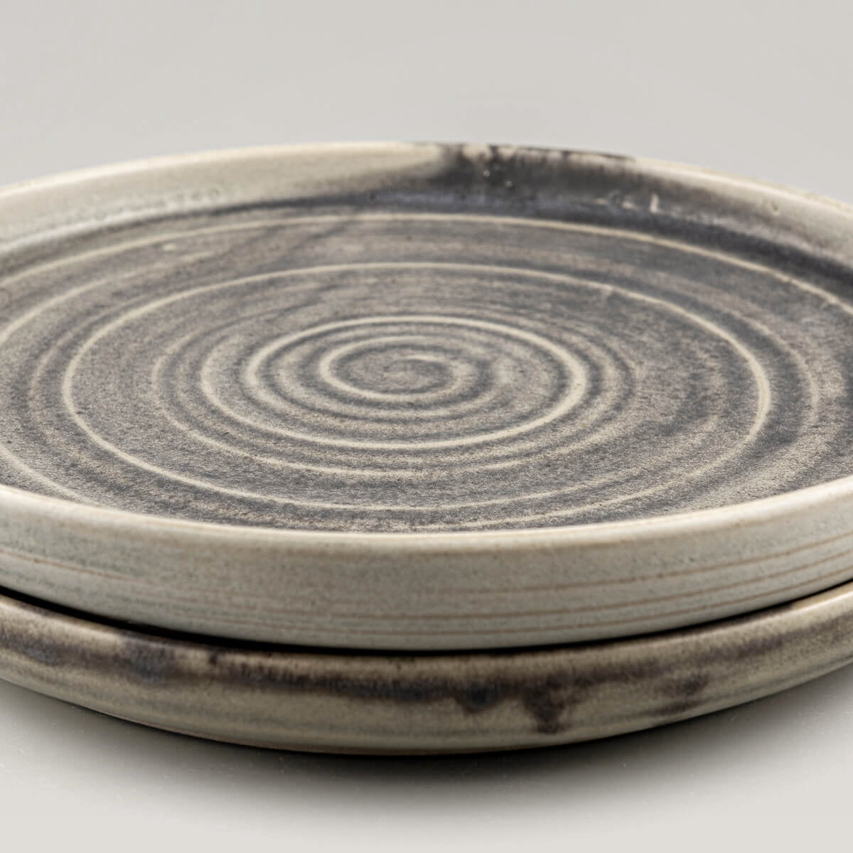 Artisanal ceramic plates close-up with precision-crafted spiral design and textured surface.