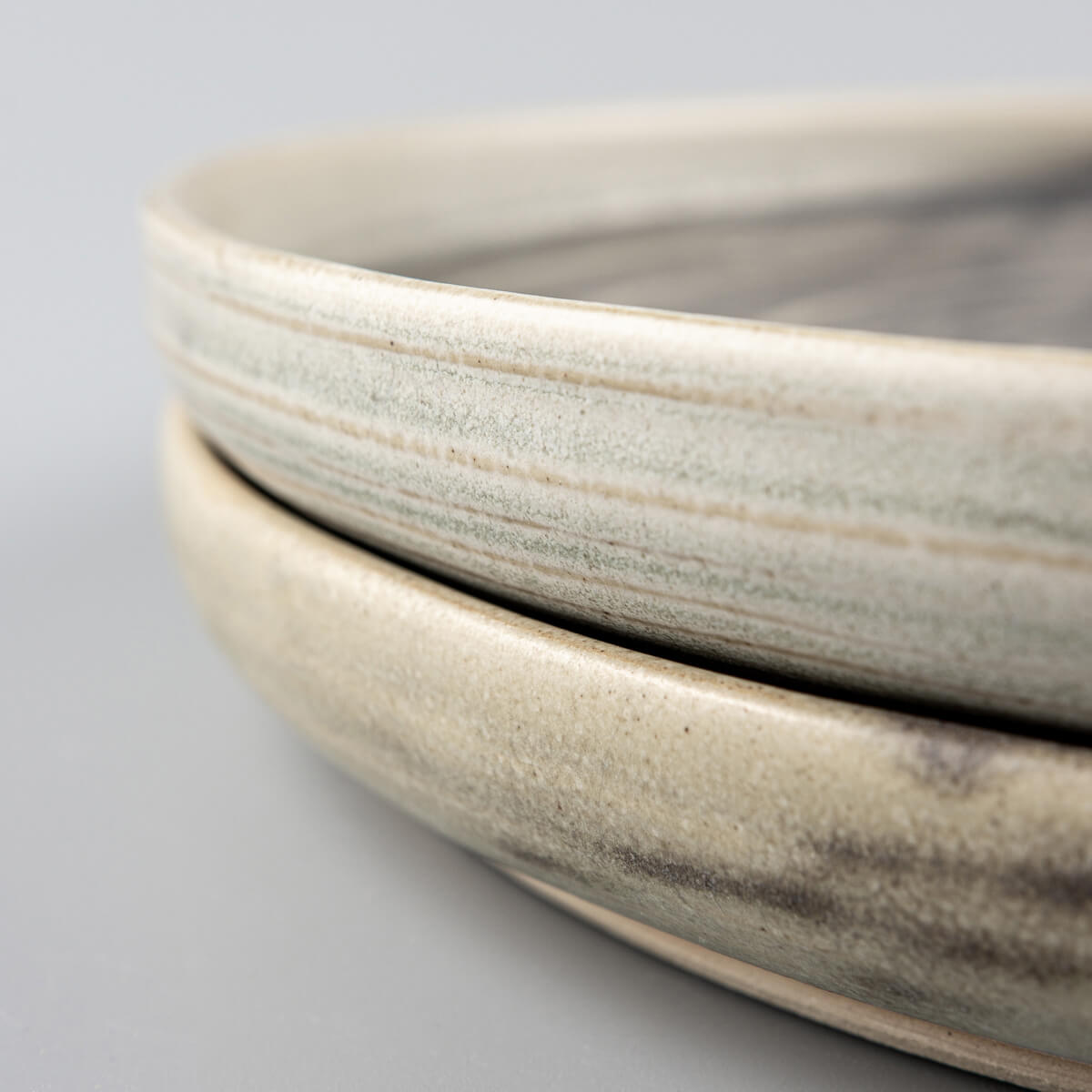 Side profile of handcrafted ceramic plates with a subtle rim and refined stoneware finish.