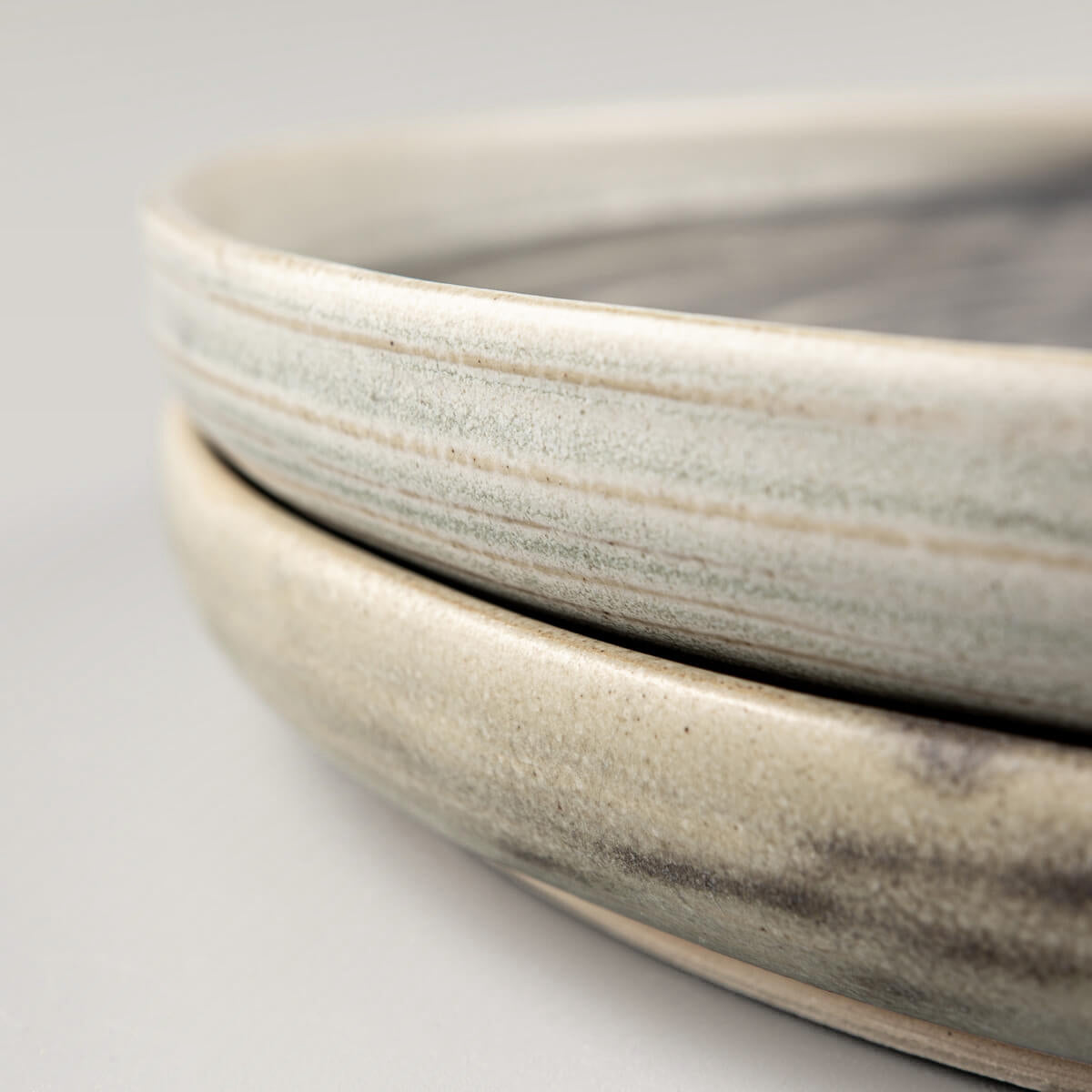 Side profile of handcrafted ceramic plates with a subtle rim and refined stoneware finish.