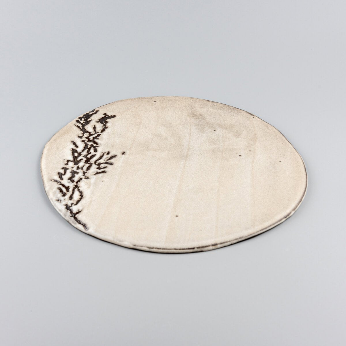 Side view of a unique ceramic plate showcasing a flat profile and artisanal craftsmanship.