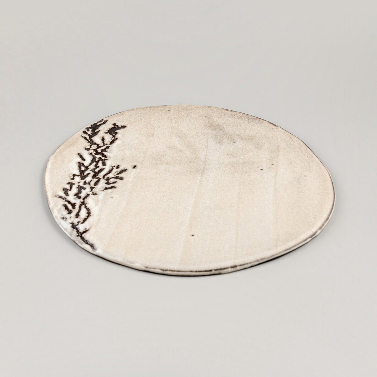 Side view of a unique ceramic plate showcasing a flat profile and artisanal craftsmanship.