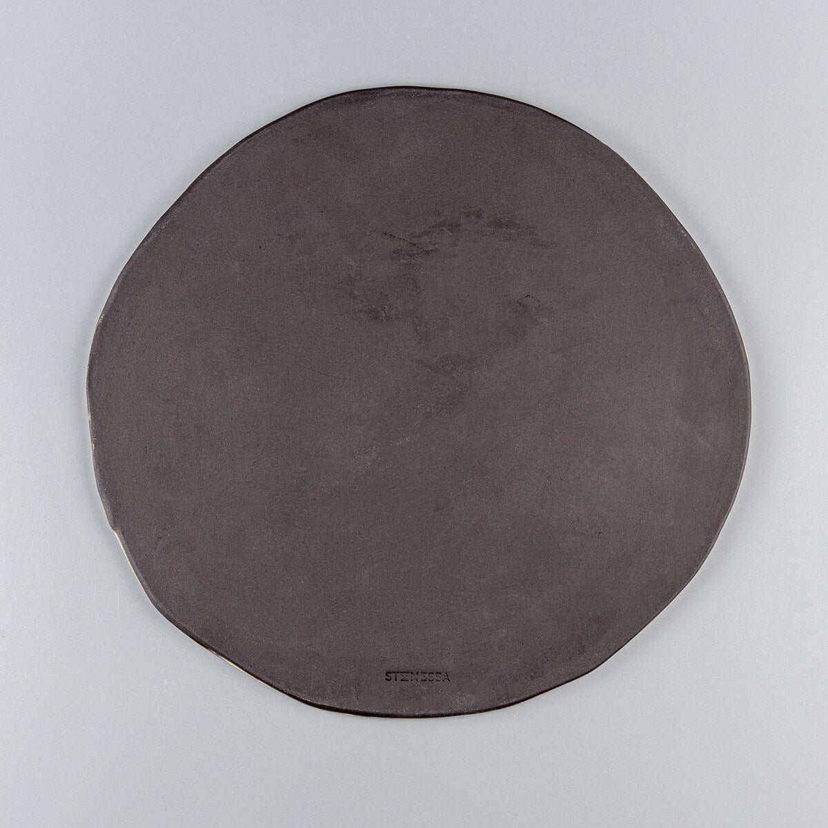 Underside of a handcrafted ceramic plate in black stoneware clay with a smooth finish.