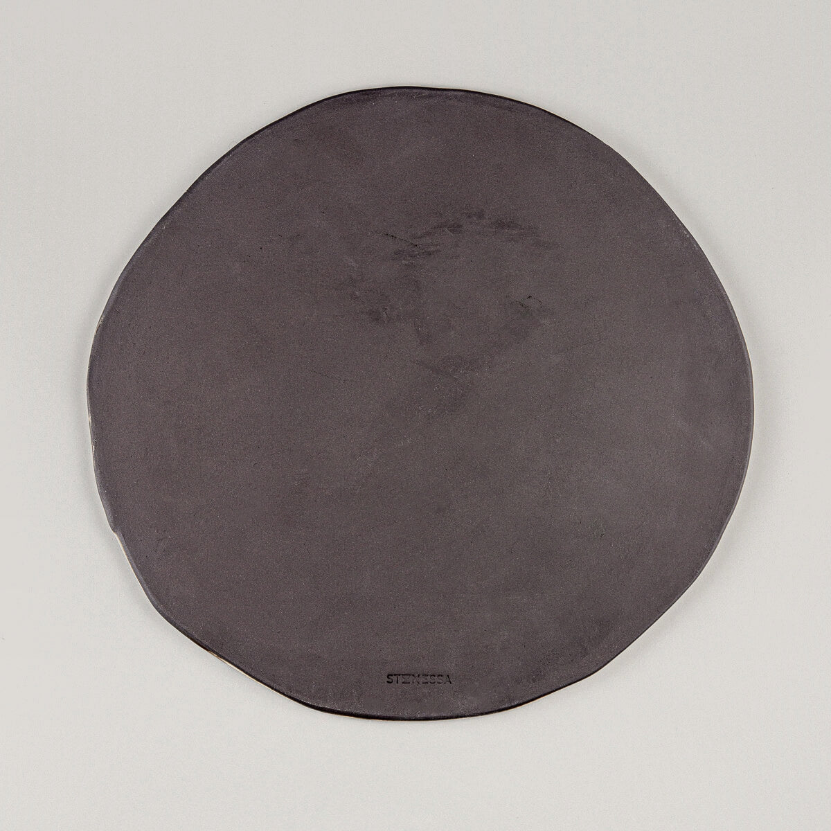 Underside of a handcrafted ceramic plate in black stoneware clay with a smooth finish.