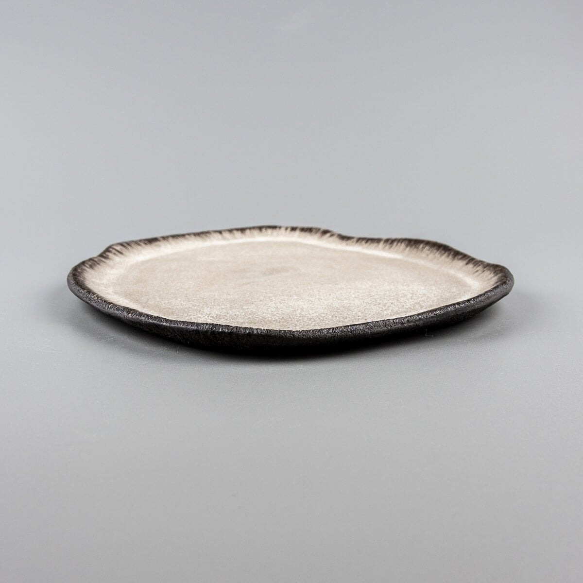 Side profile of artisan ceramic plate with raised edges for refined food presentation.