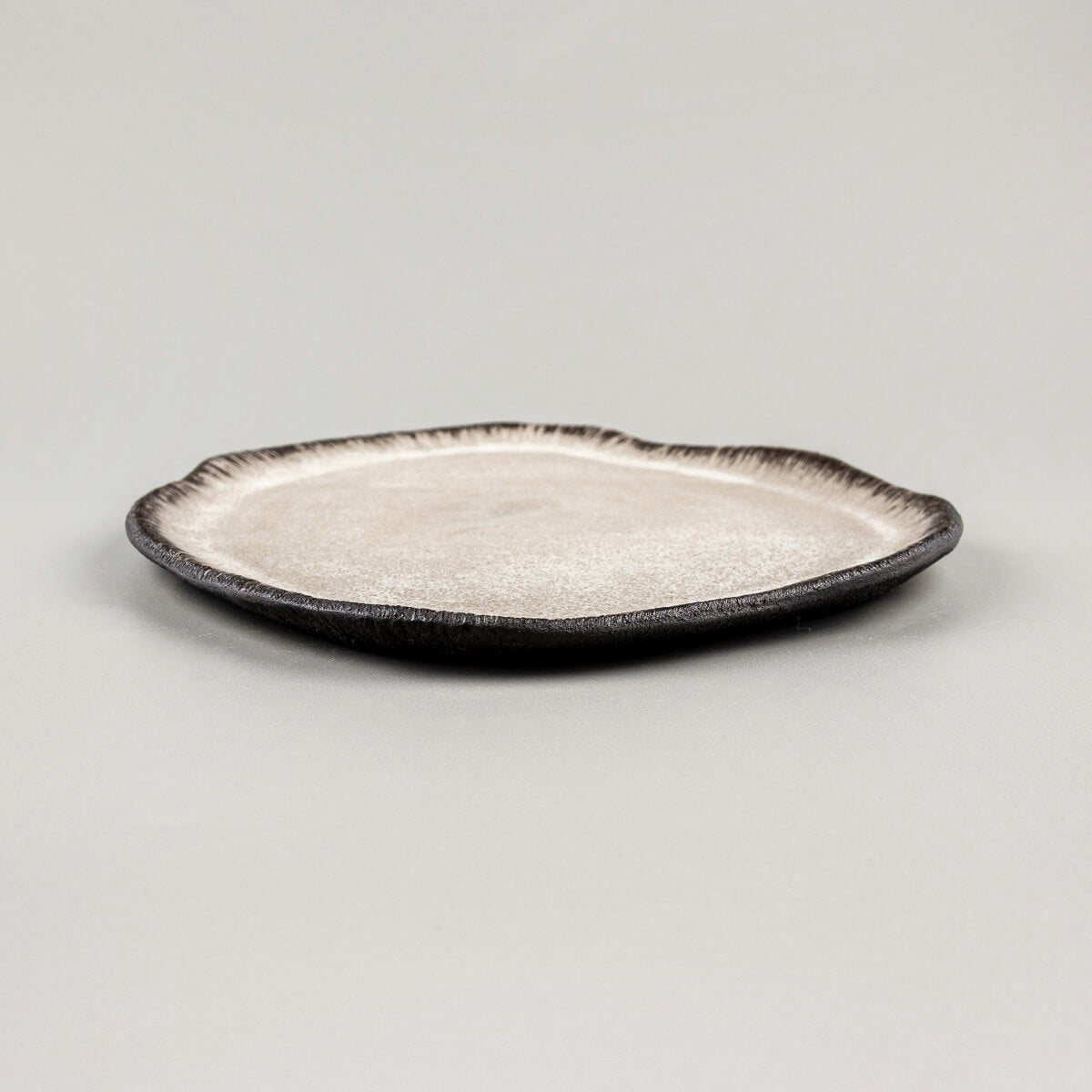 Side profile of artisan ceramic plate with raised edges for refined food presentation.