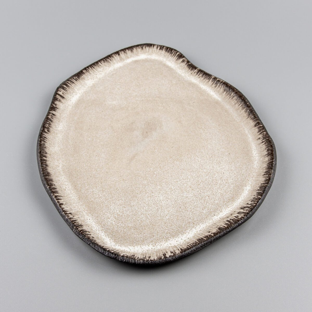 Handcrafted ceramic plate with organic asymmetric shape, perfect for premium culinary plating.
