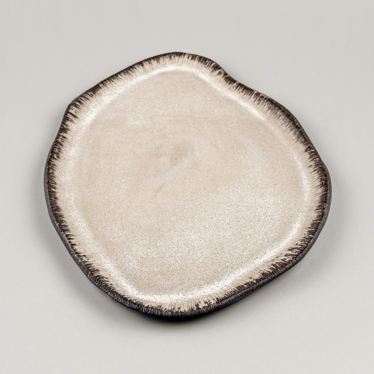 Handcrafted ceramic plate with organic asymmetric shape, perfect for premium culinary plating.