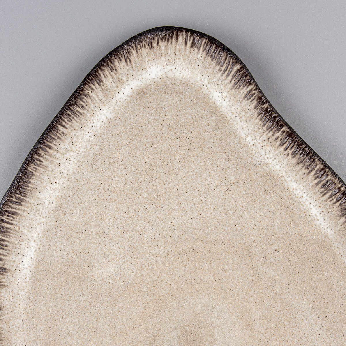 Close-up of textured ceramic rim with hand-applied dashes and matte glaze finish.