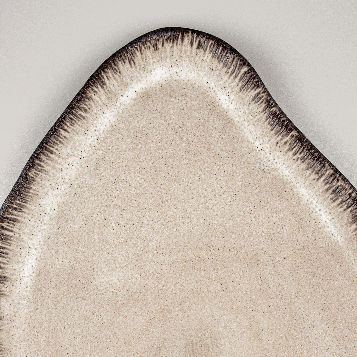 Close-up of textured ceramic rim with hand-applied dashes and matte glaze finish.