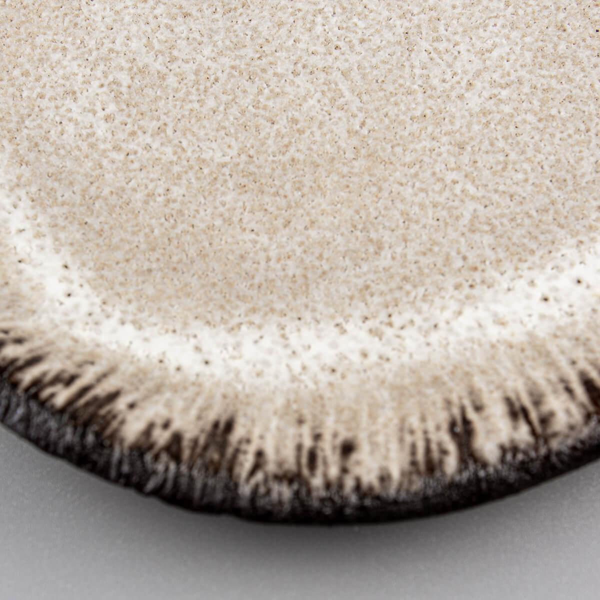 Textured edge of ceramic plate highlighting hand-applied artistic details.