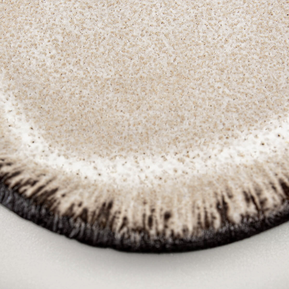 Textured edge of ceramic plate highlighting hand-applied artistic details.