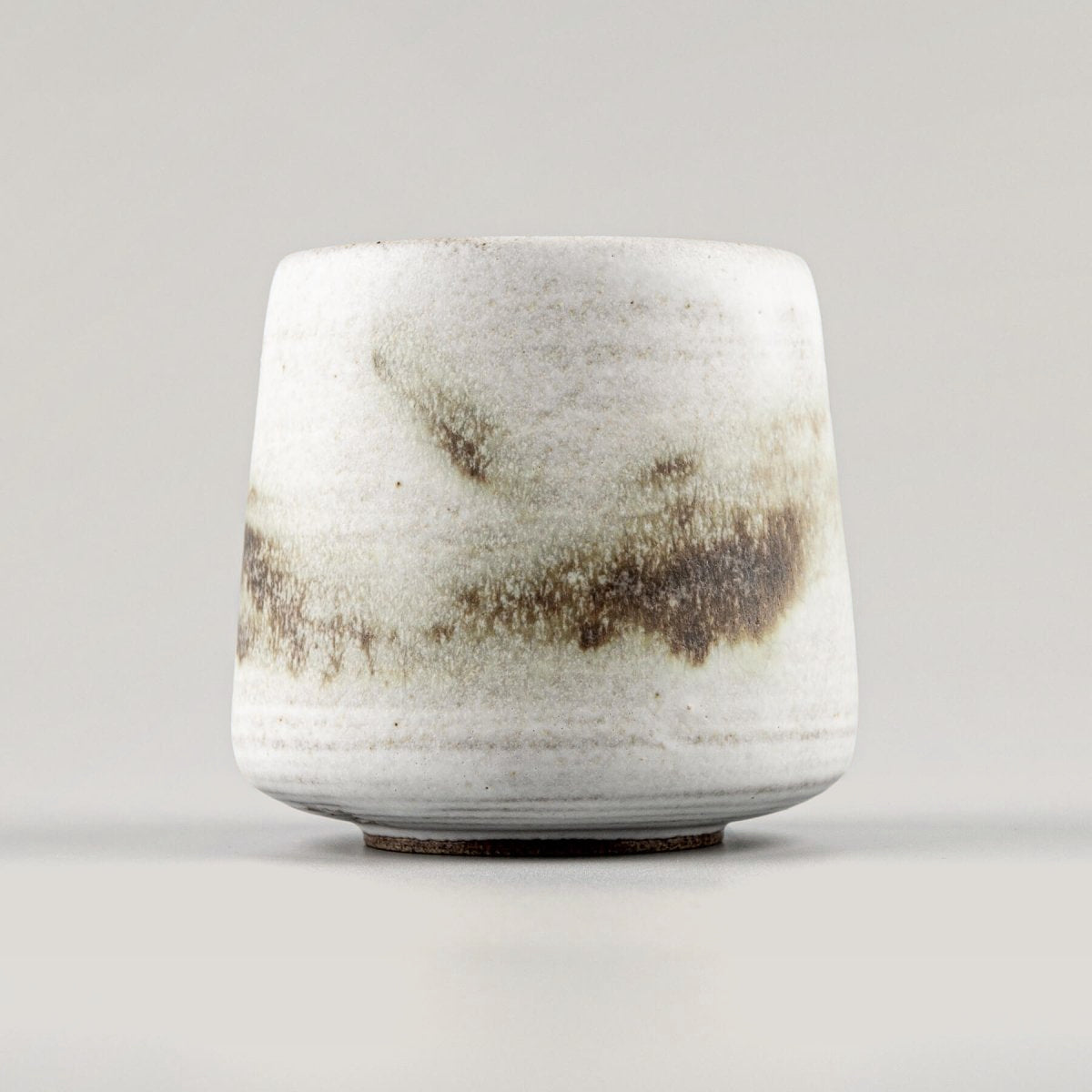 Handcrafted ceramic espresso cup with white matte glaze and copper oxide accents for fine dining presentation.