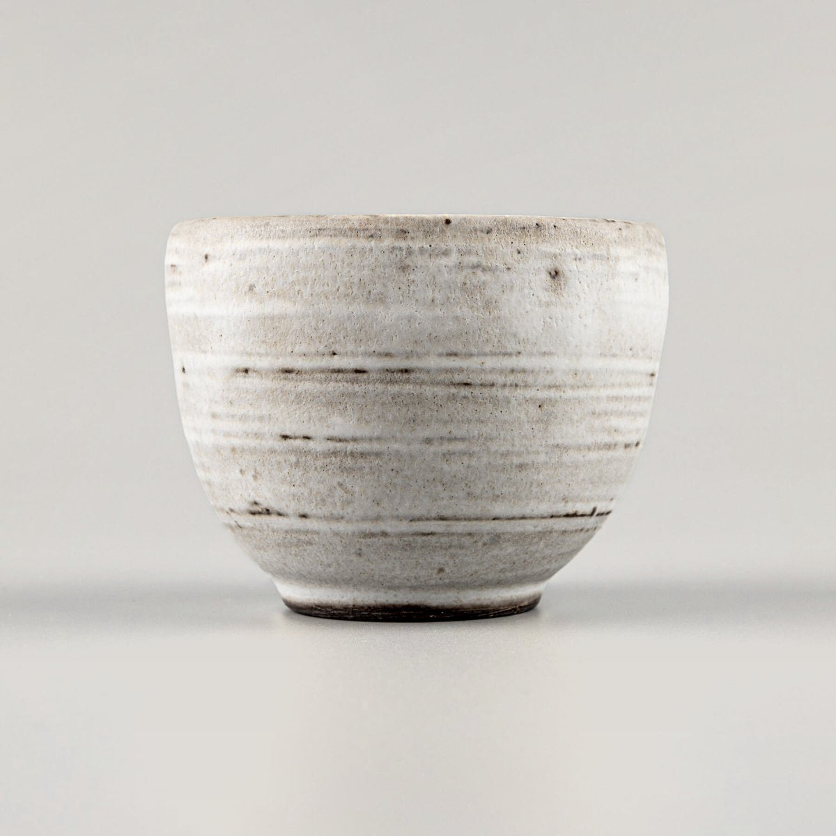Handmade coffee mugs with white matte glaze, crafted from dark stoneware clay for unique artisanal tableware.