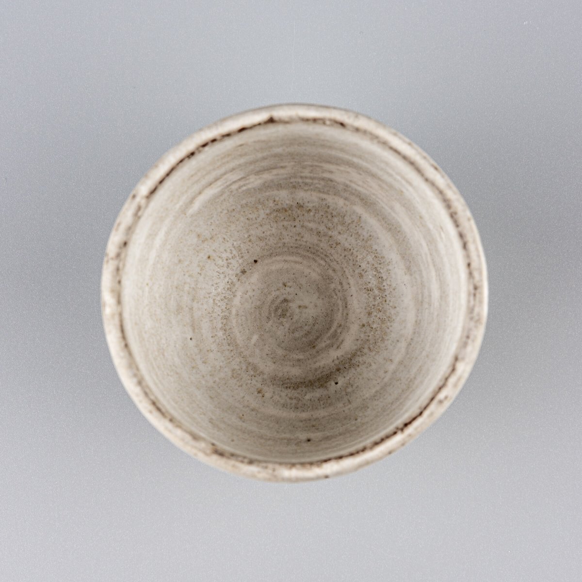 Artisanal stoneware coffee mug with a round shape and subtle textures, designed for interior design and collectors.