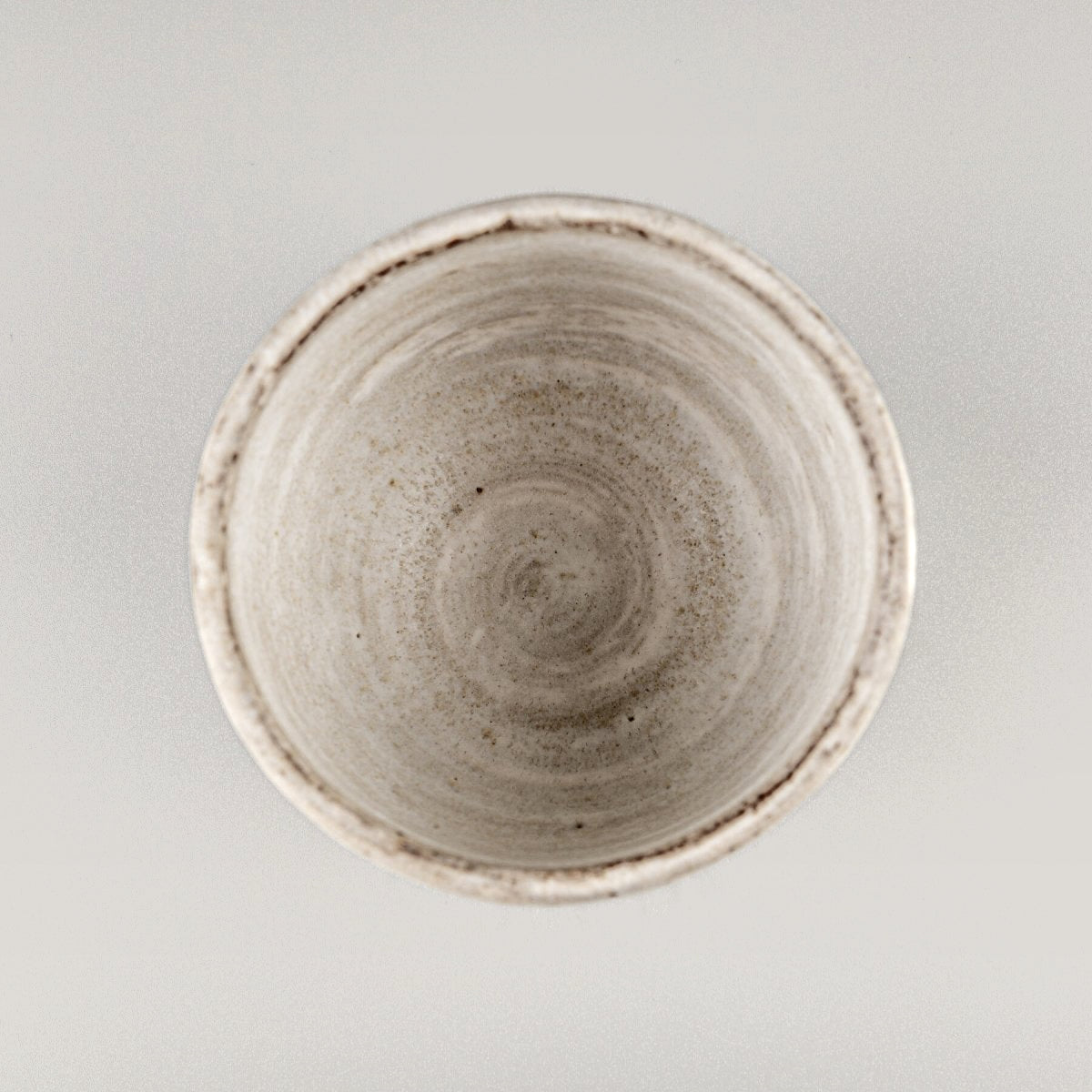 Artisanal stoneware coffee mug with a round shape and subtle textures, designed for interior design and collectors.