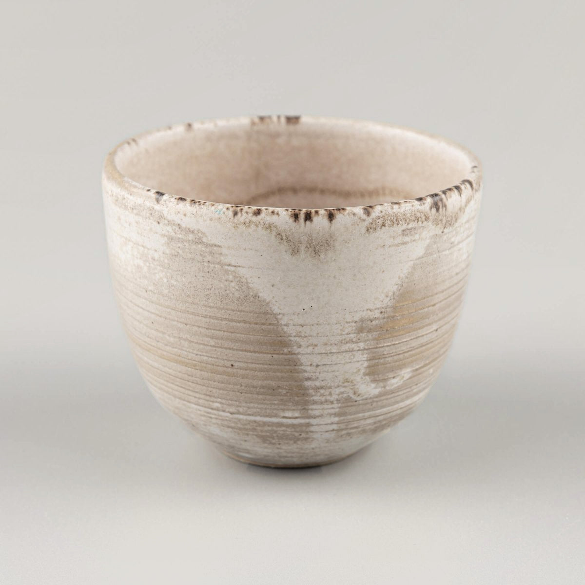 Artisan stoneware coffee cups with engraved lines and rustic matte finish for modern culinary presentation.