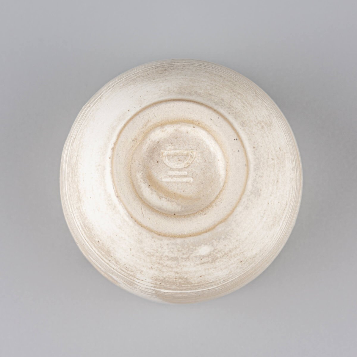 Stoneware coffee cup bottom with potter’s wheel detail, showcasing artisanal craftsmanship.