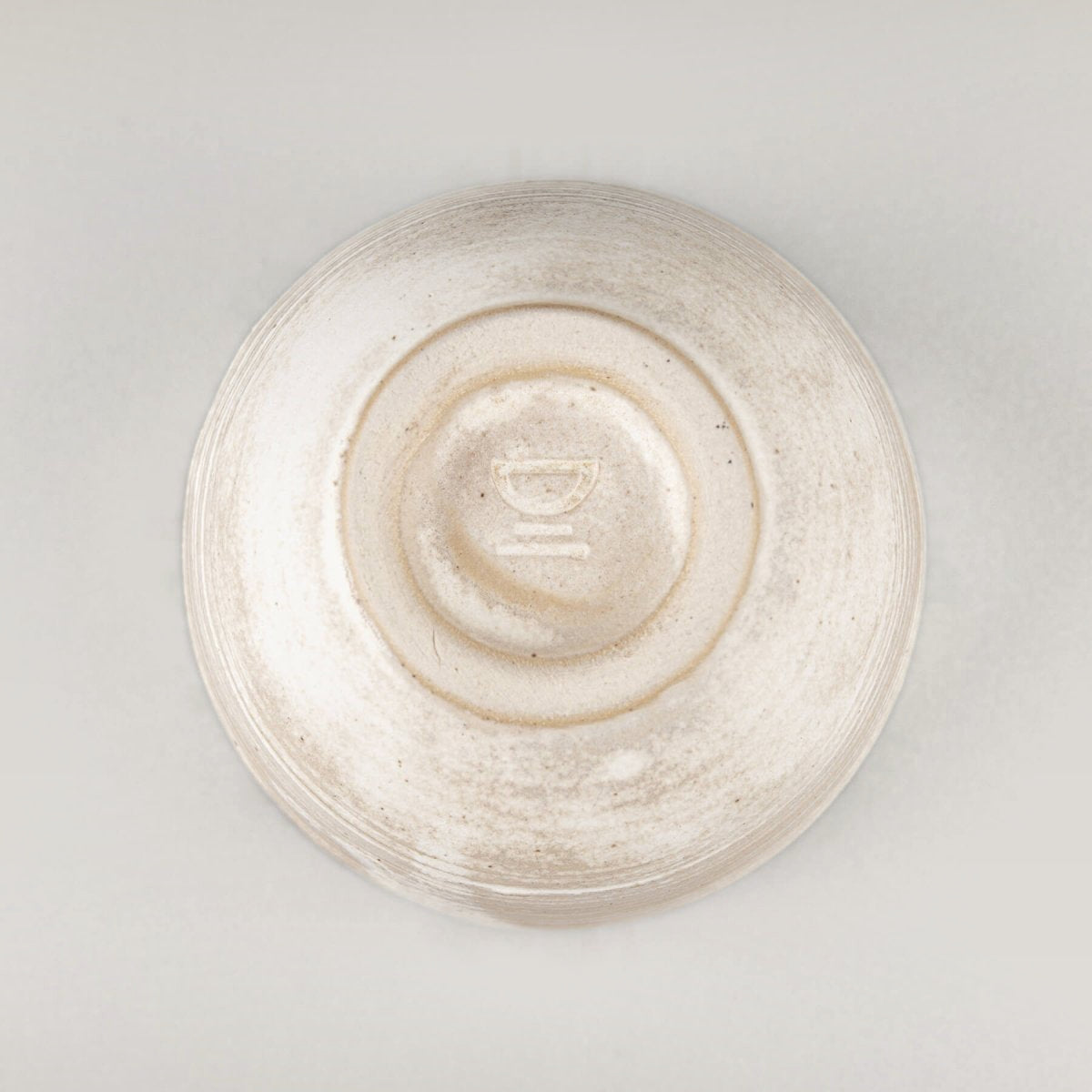 Stoneware coffee cup bottom with potter’s wheel detail, showcasing artisanal craftsmanship.