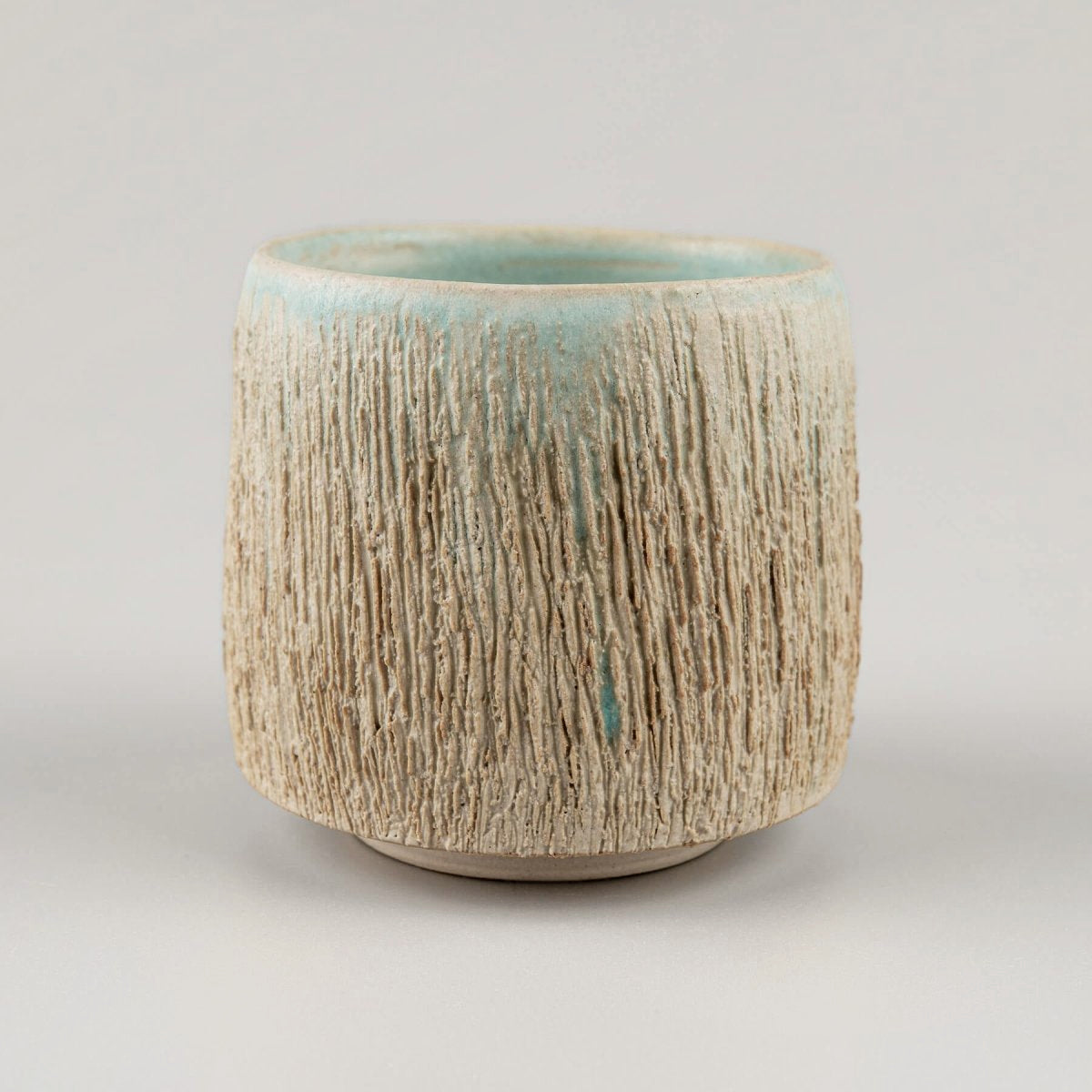 Handcrafted ceramic mugs with rustic carved texture, ideal for boutique hotels and restaurants.