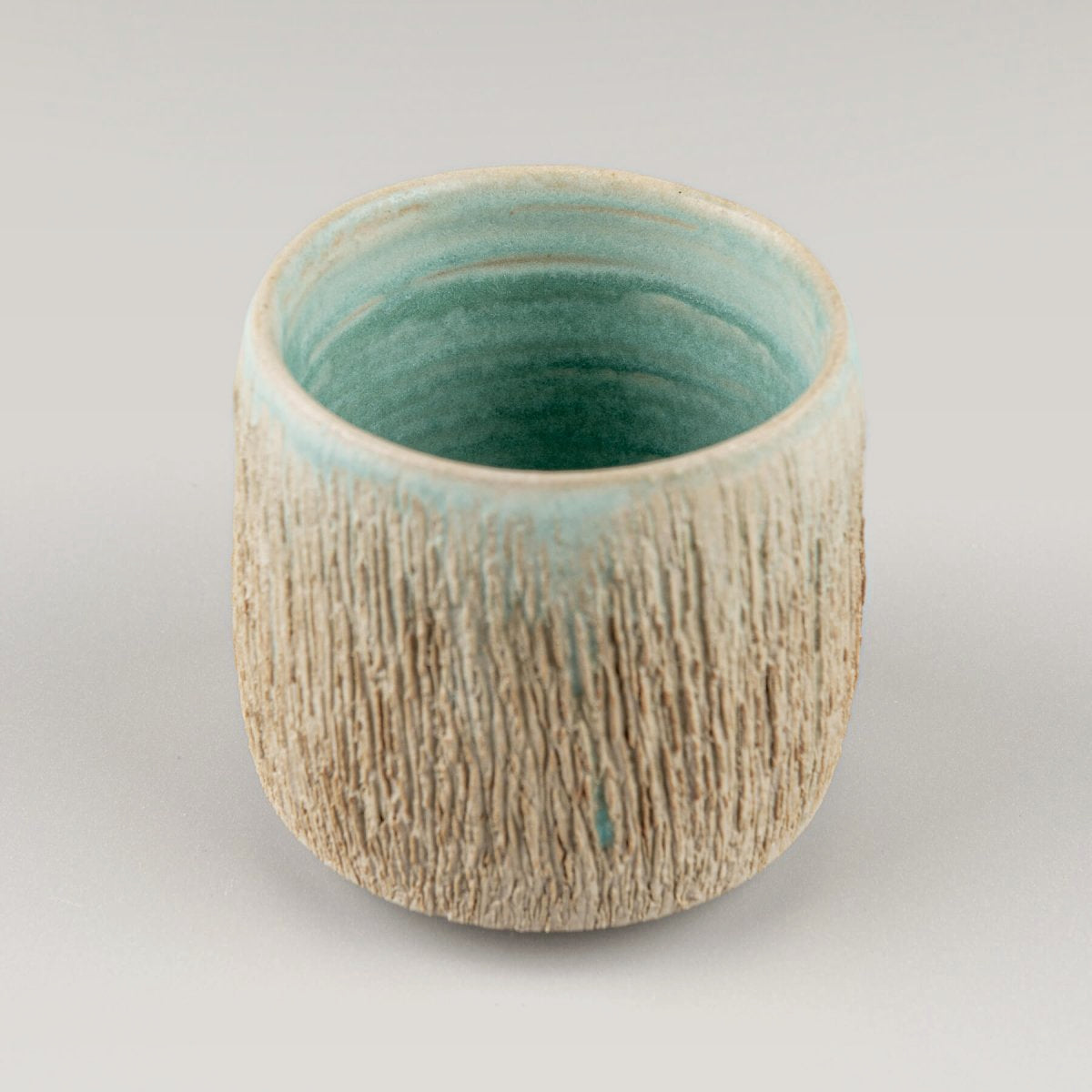 Artisanal textured ceramic mug with aqua interior, collectible pottery for private collectors.