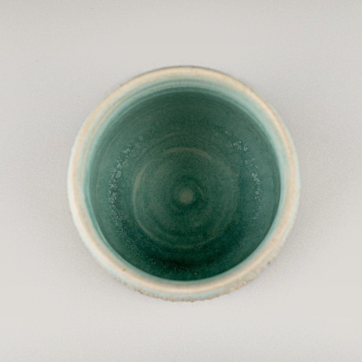 Top view of aqua glazed ceramic mug, handmade pottery for fine dining and culinary use.