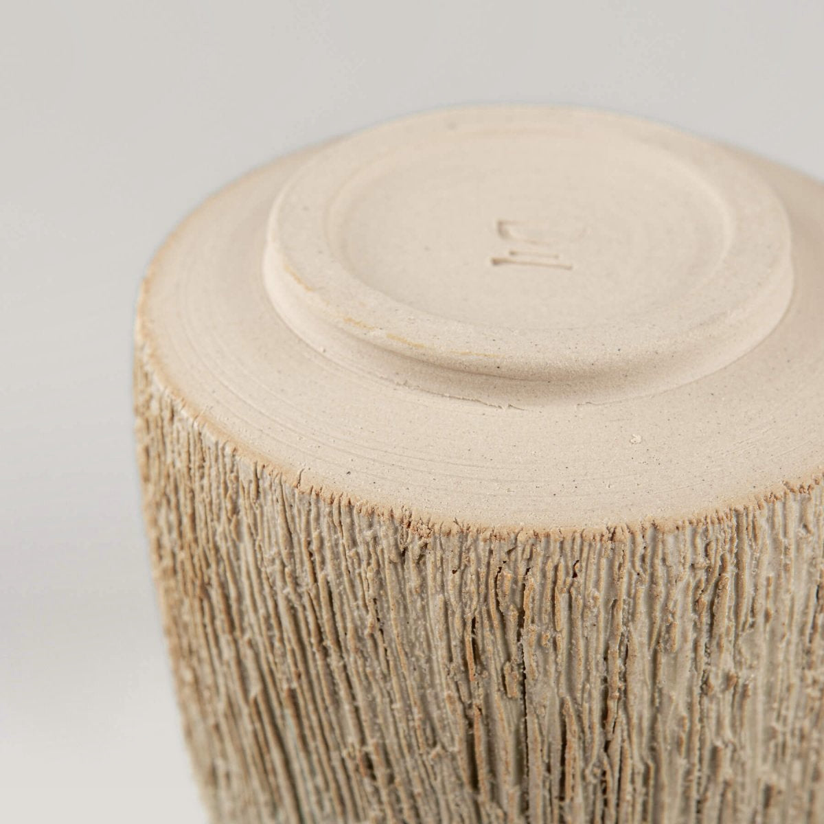 Close-up of rustic carved texture on pottery mug, artisanal ceramic tableware for restaurants.