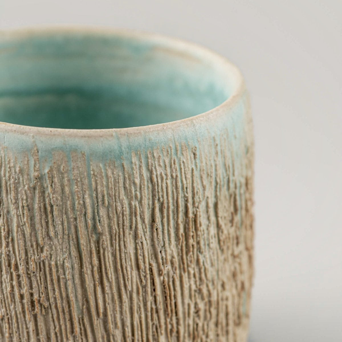 Detail of textured ceramic surface with turquoise accents, collectible pottery for fine dining.