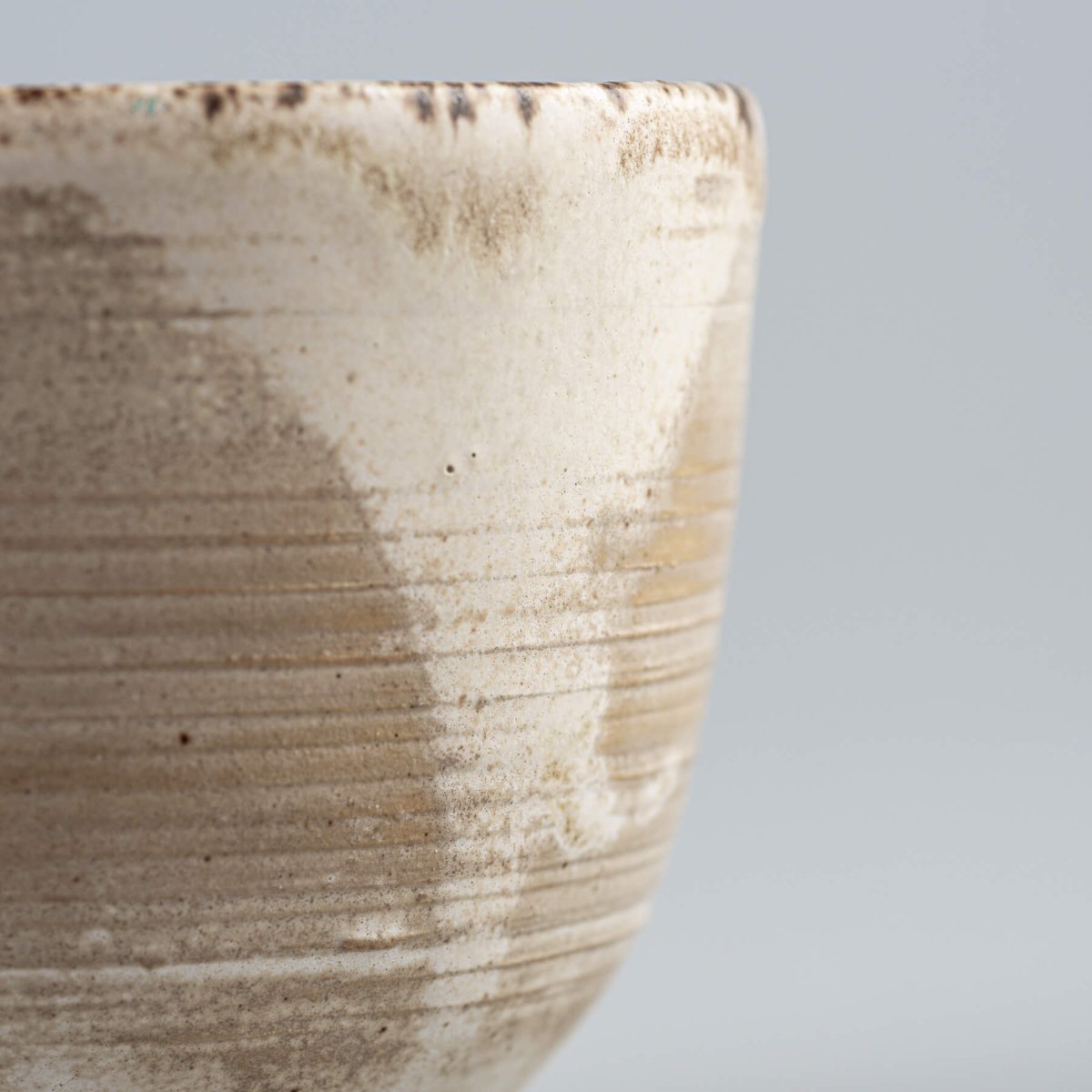 Side profile of artisan stoneware coffee cup with engraved lines and matte glaze, perfect for collectible pottery.