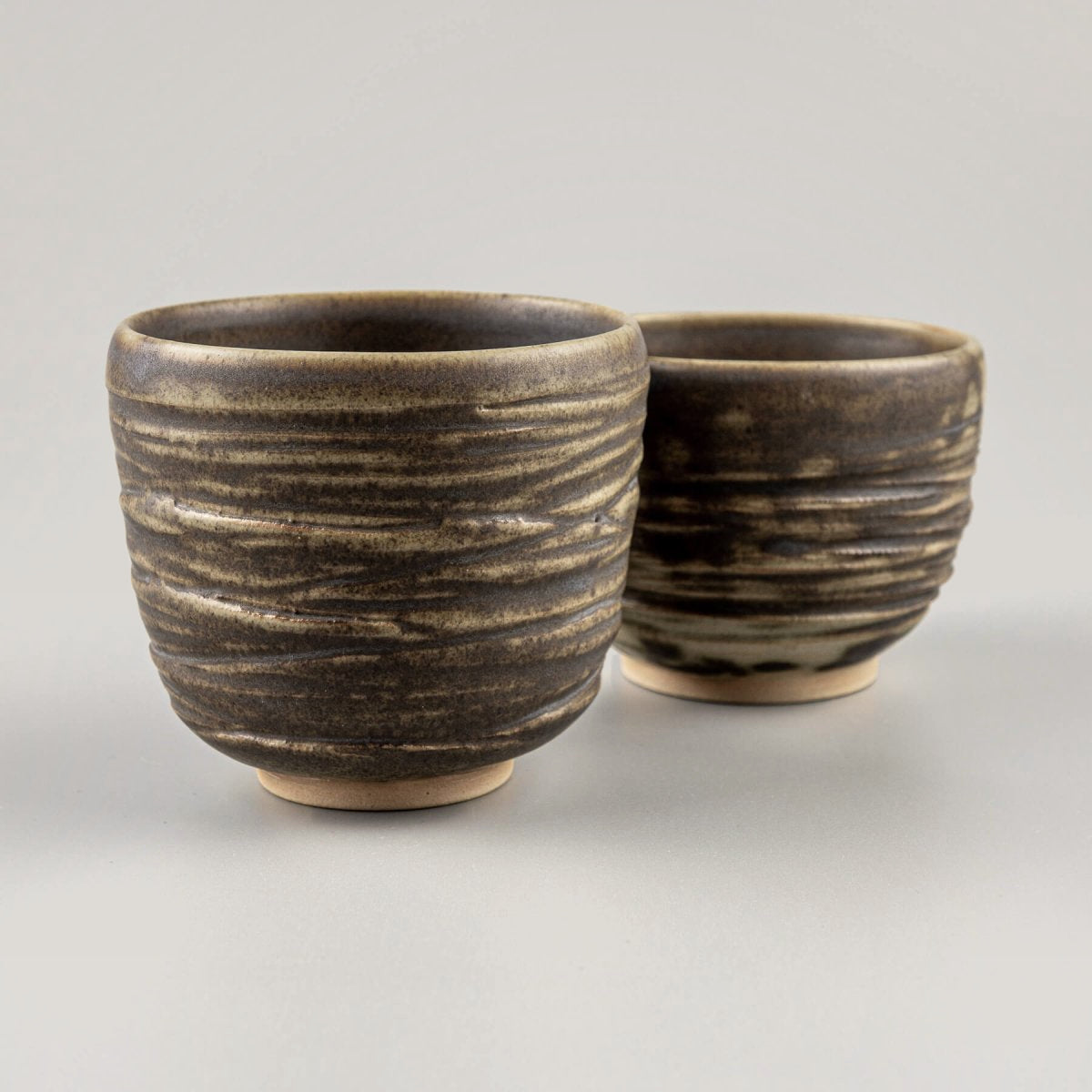 Artisanal ceramic mugs in earthy tones with natural texture, perfect for interior design, collectible pottery, and gift ideas