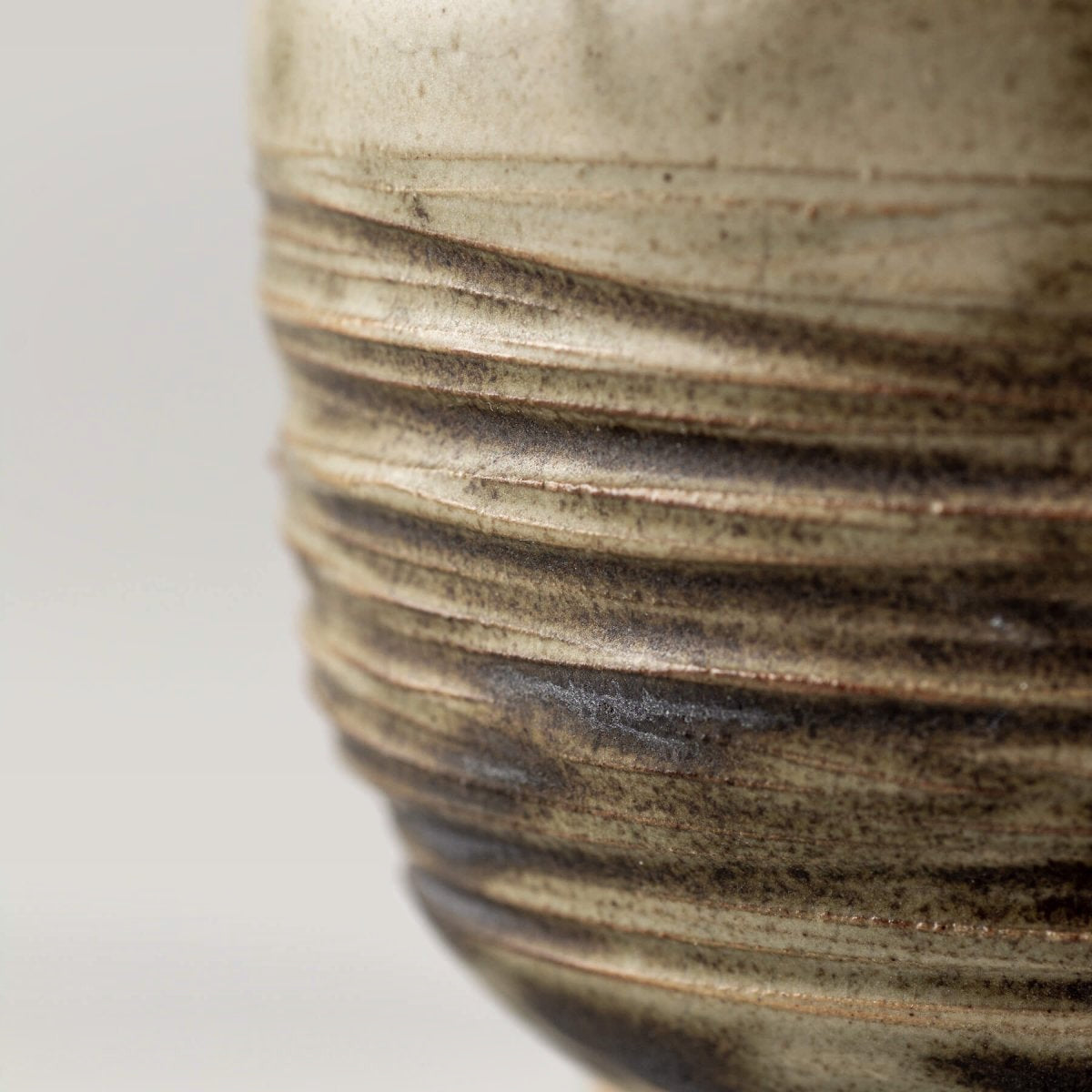 Close-up of carved ceramic texture with earthy olive tones, artisanal tableware for home and boutique hotels.