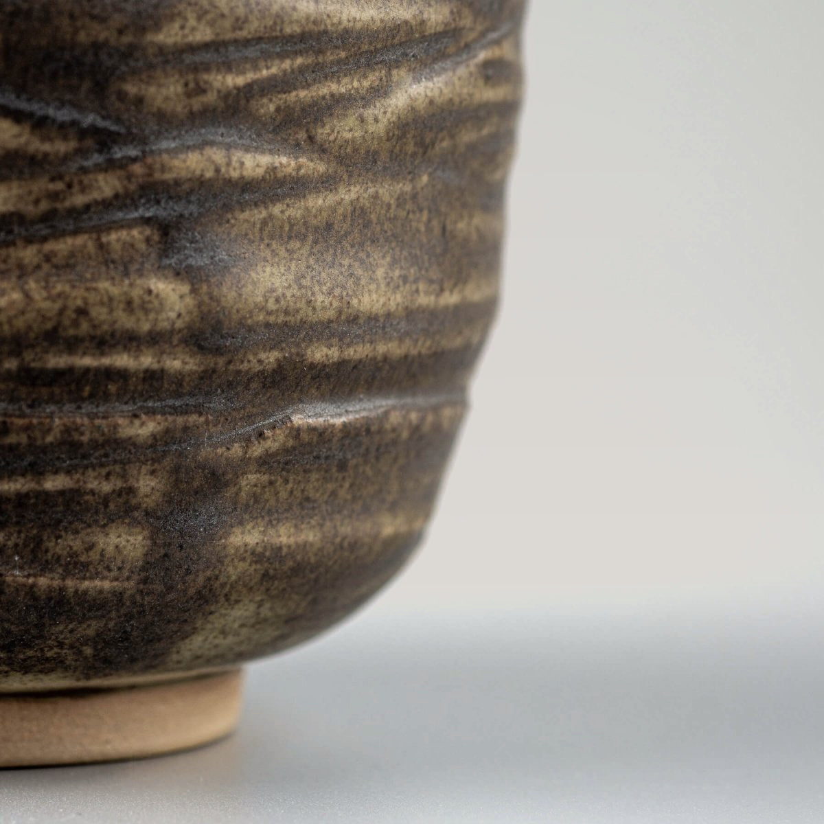 Side view of artisanal ceramic mug with engraved lines and olive-green glaze, collectible handmade decor.