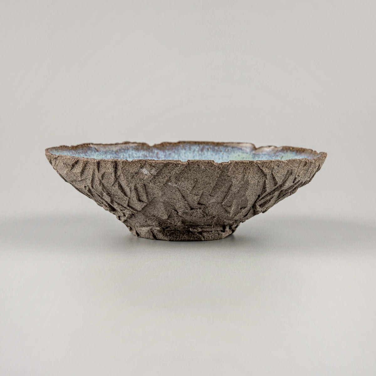 Side view of handmade bowl with rough exterior and curved form.