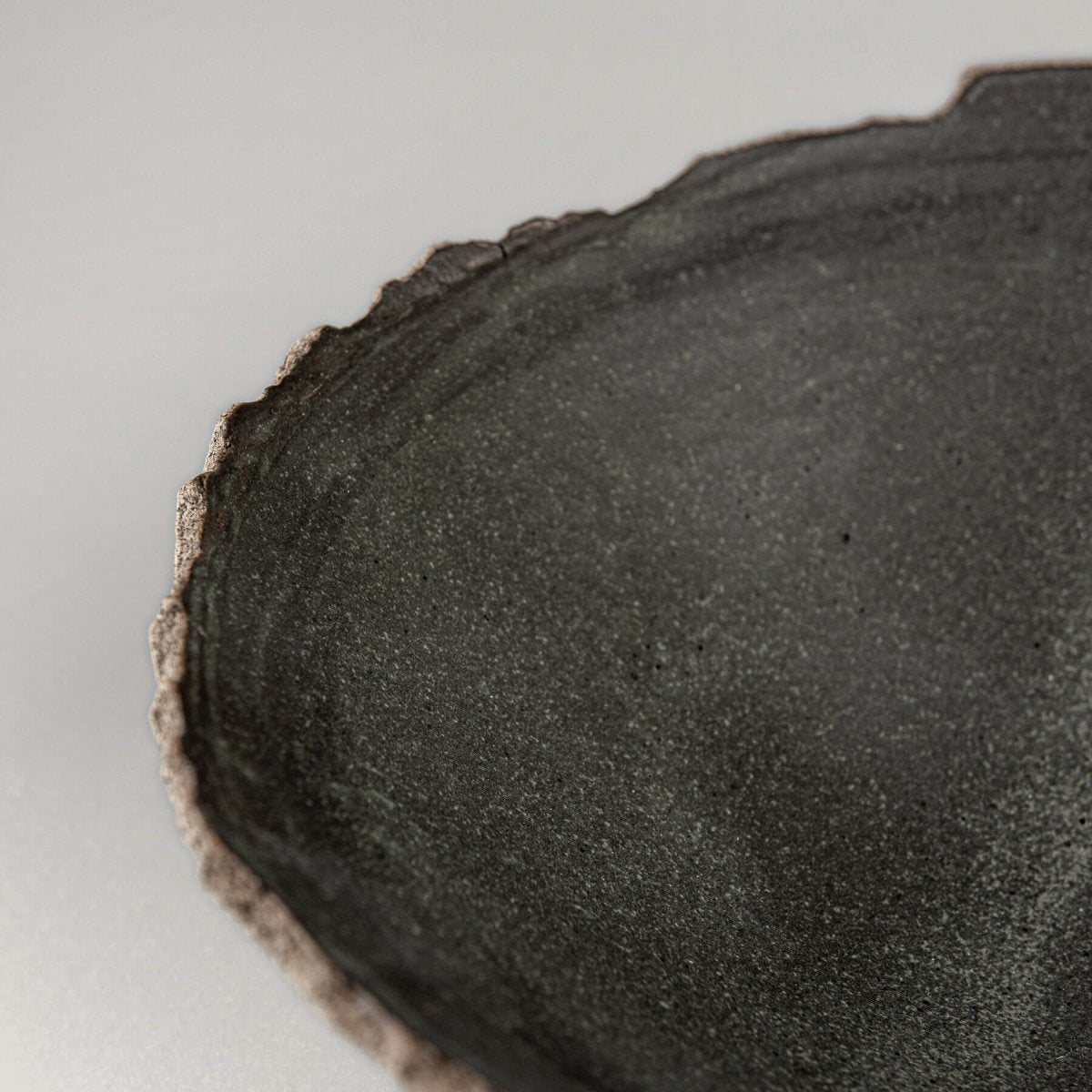Close-up of uneven hand-shaped rim and natural clay texture on handcrafted bowl for home use.