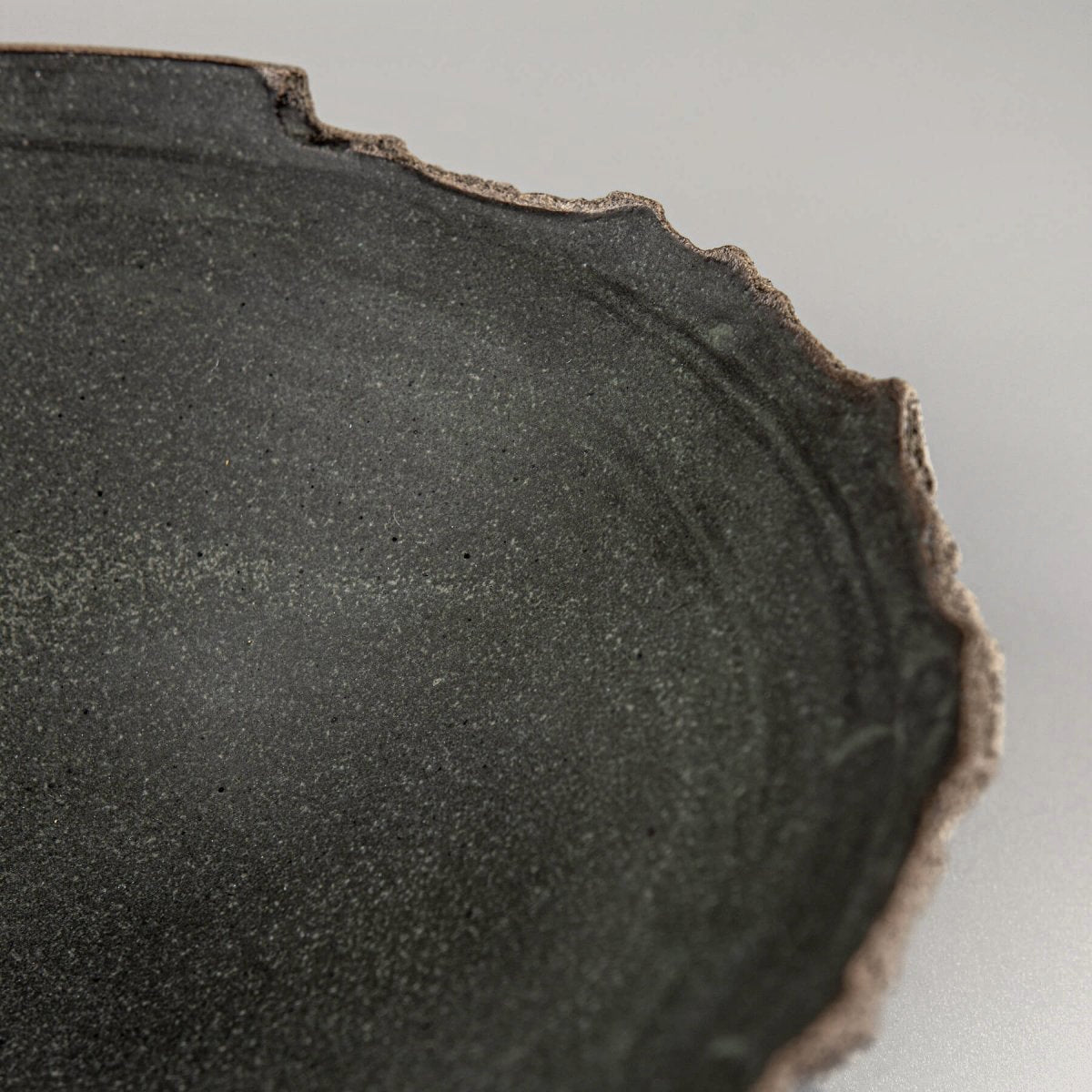 Close-up of uneven hand-shaped rim and natural clay texture on handcrafted bowl for home use.