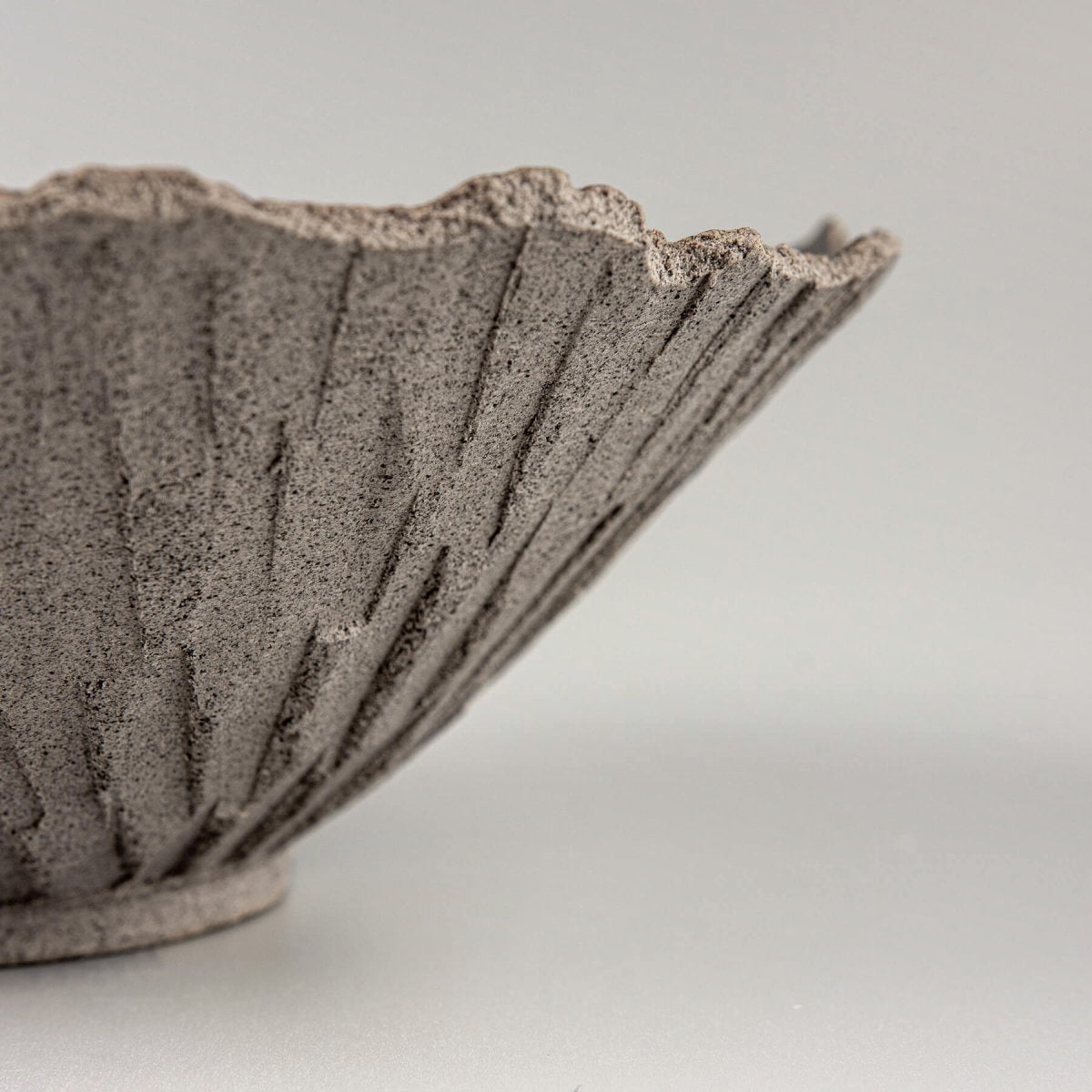 Artisan ceramic bowl highlighting radial carving details and unglazed natural finish, perfect for collectors.