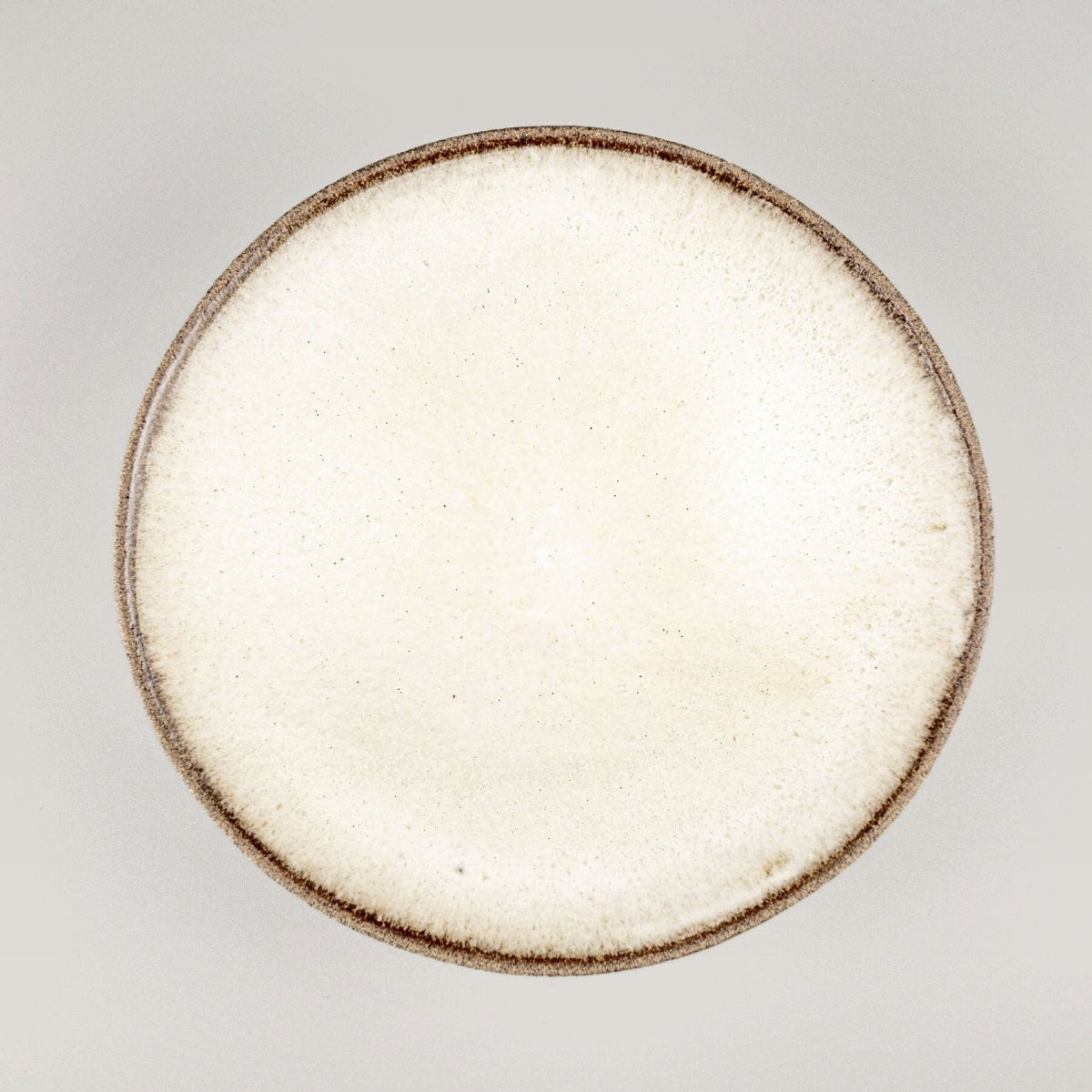Handmade artisanal ceramic plate with white matte glaze interior for fine dining presentation.