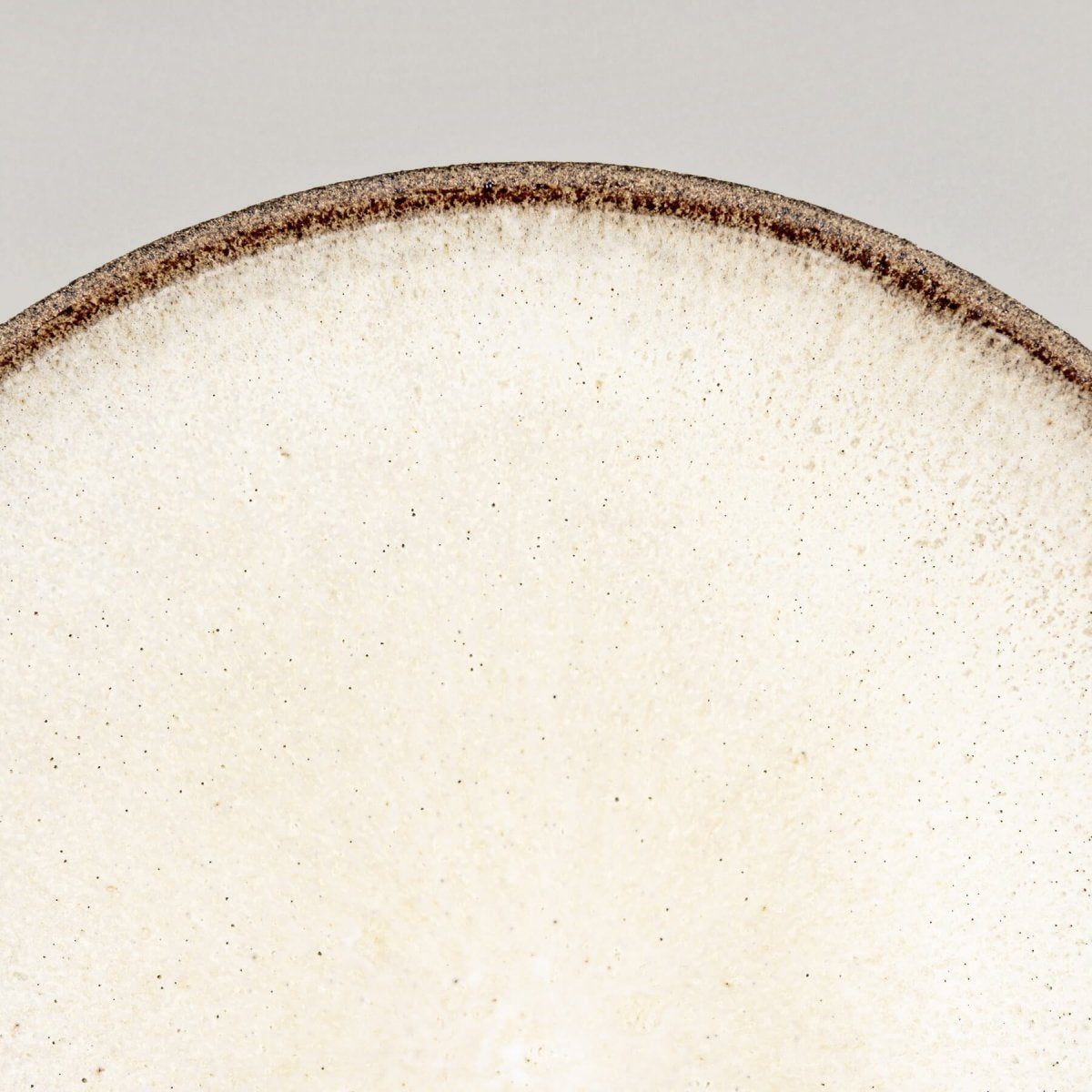 Close-up of artisanal ceramic plate showcasing textured stoneware exterior and minimalist design.