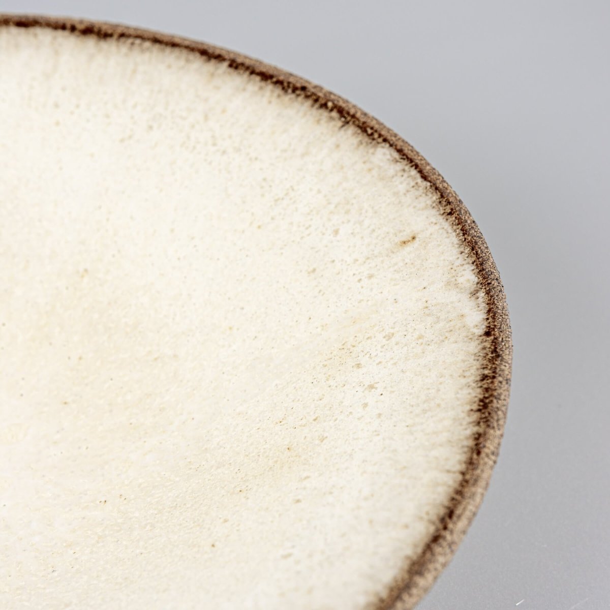 Detail of matte glaze transition to unglazed textured rim on artisanal ceramic plate.