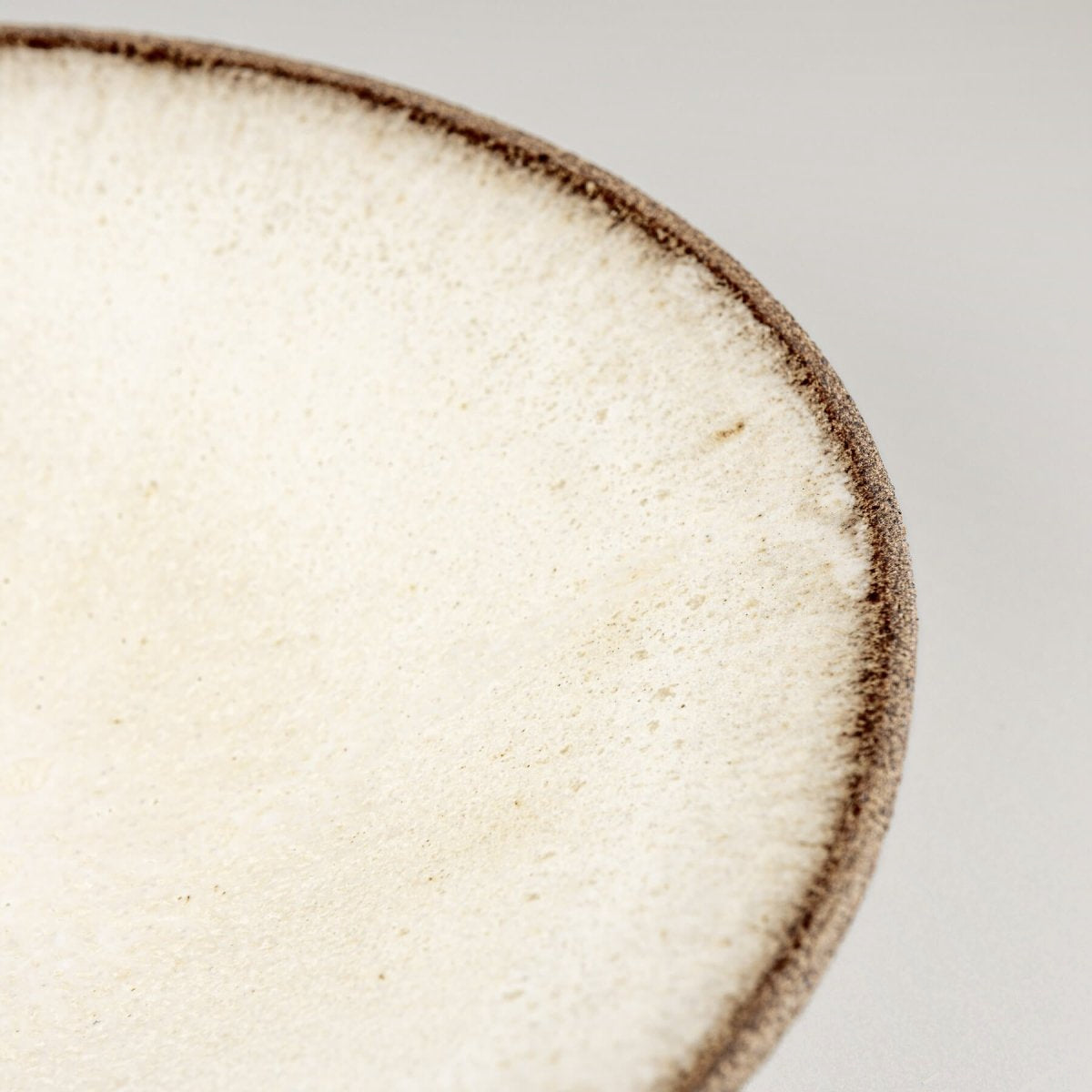 Detail of matte glaze transition to unglazed textured rim on artisanal ceramic plate.