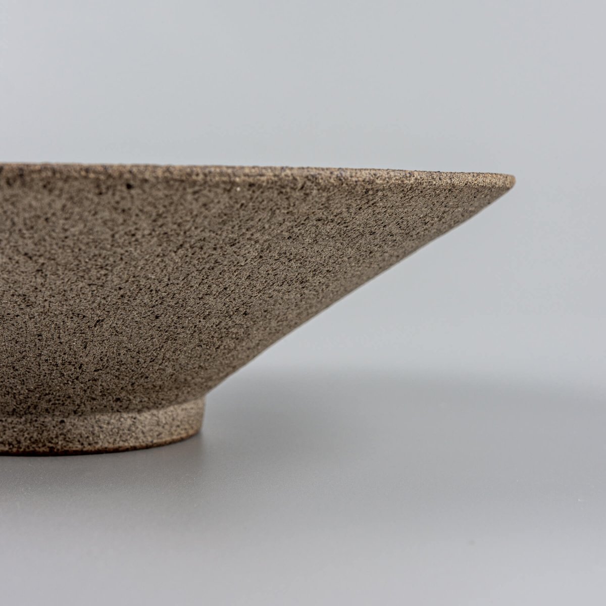 Close-up of a finely crafted rim on a handmade ceramic plate for luxury dining.