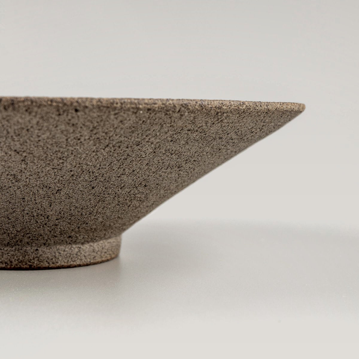 Close-up of a finely crafted rim on a handmade ceramic plate for luxury dining.