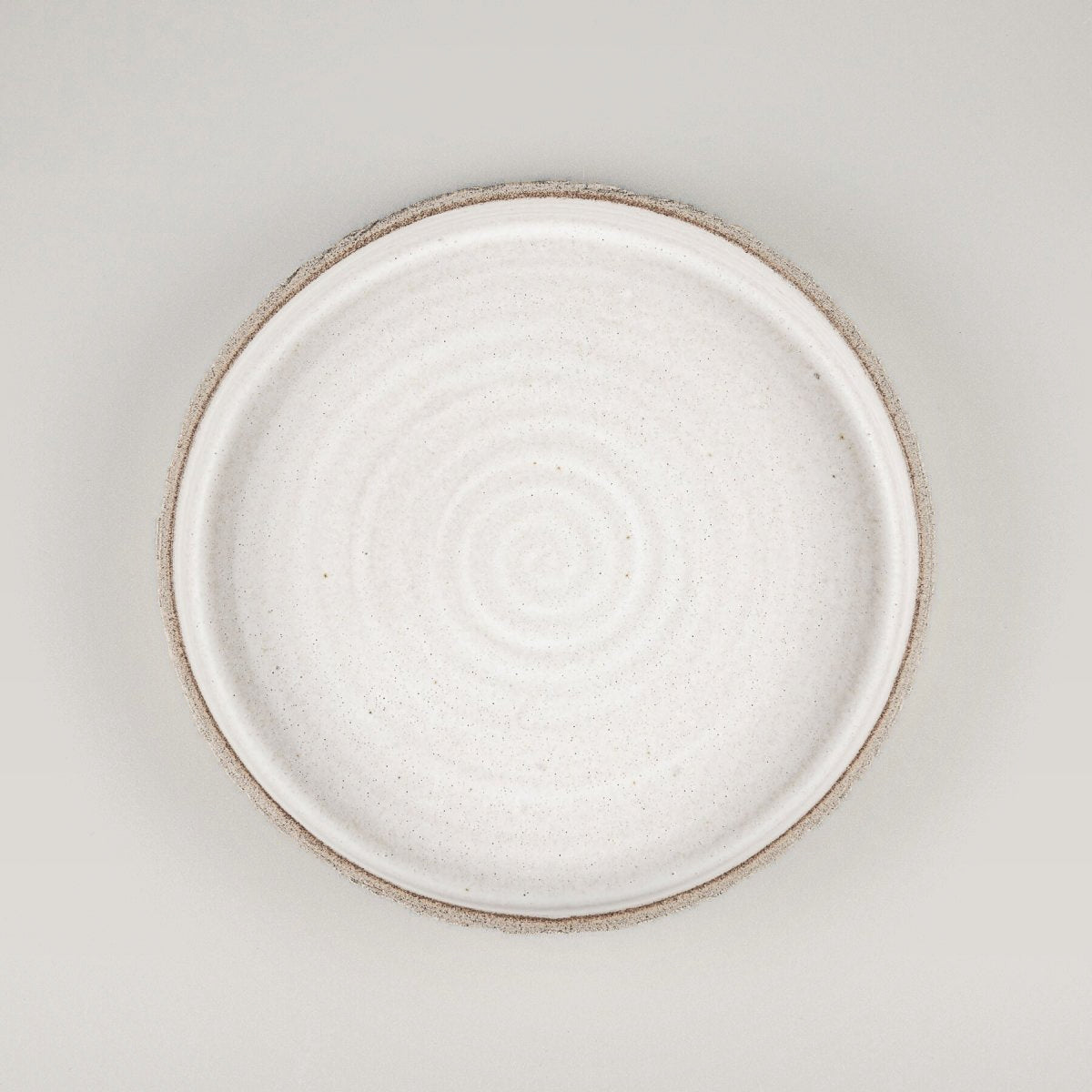 Top view of matte white ceramic plate with minimalist spiral center pattern.