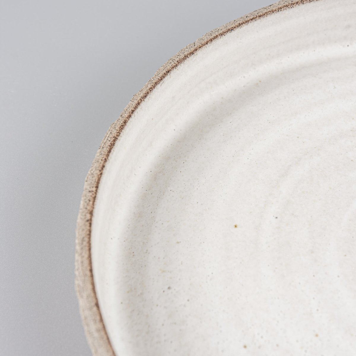 Close-up of a white matte-glazed handmade plate with a detailed spiral design for upscale restaurants.