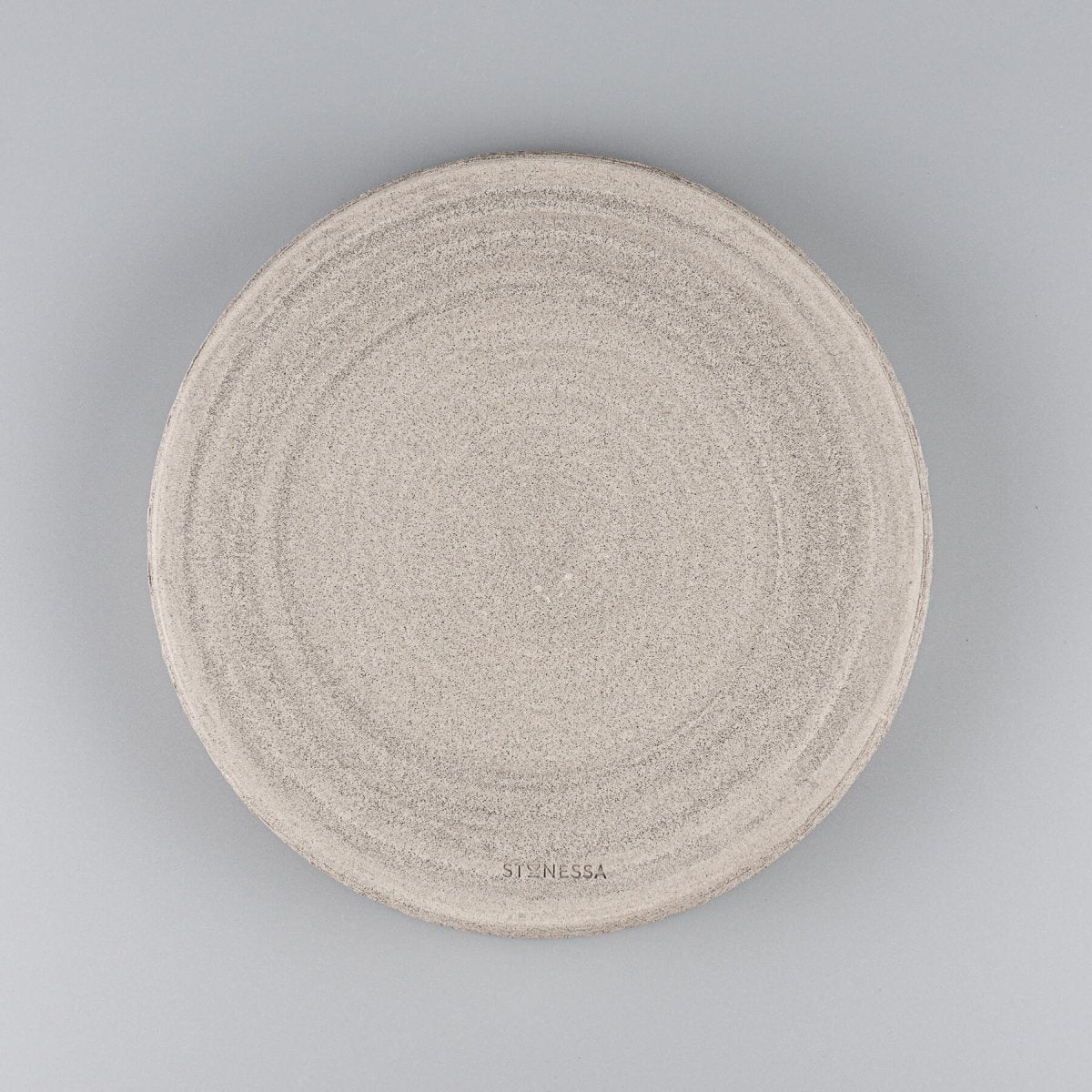 Elegant handmade ceramic plate with textured unglazed exterior and smooth white matte glazed interior for fine dining.